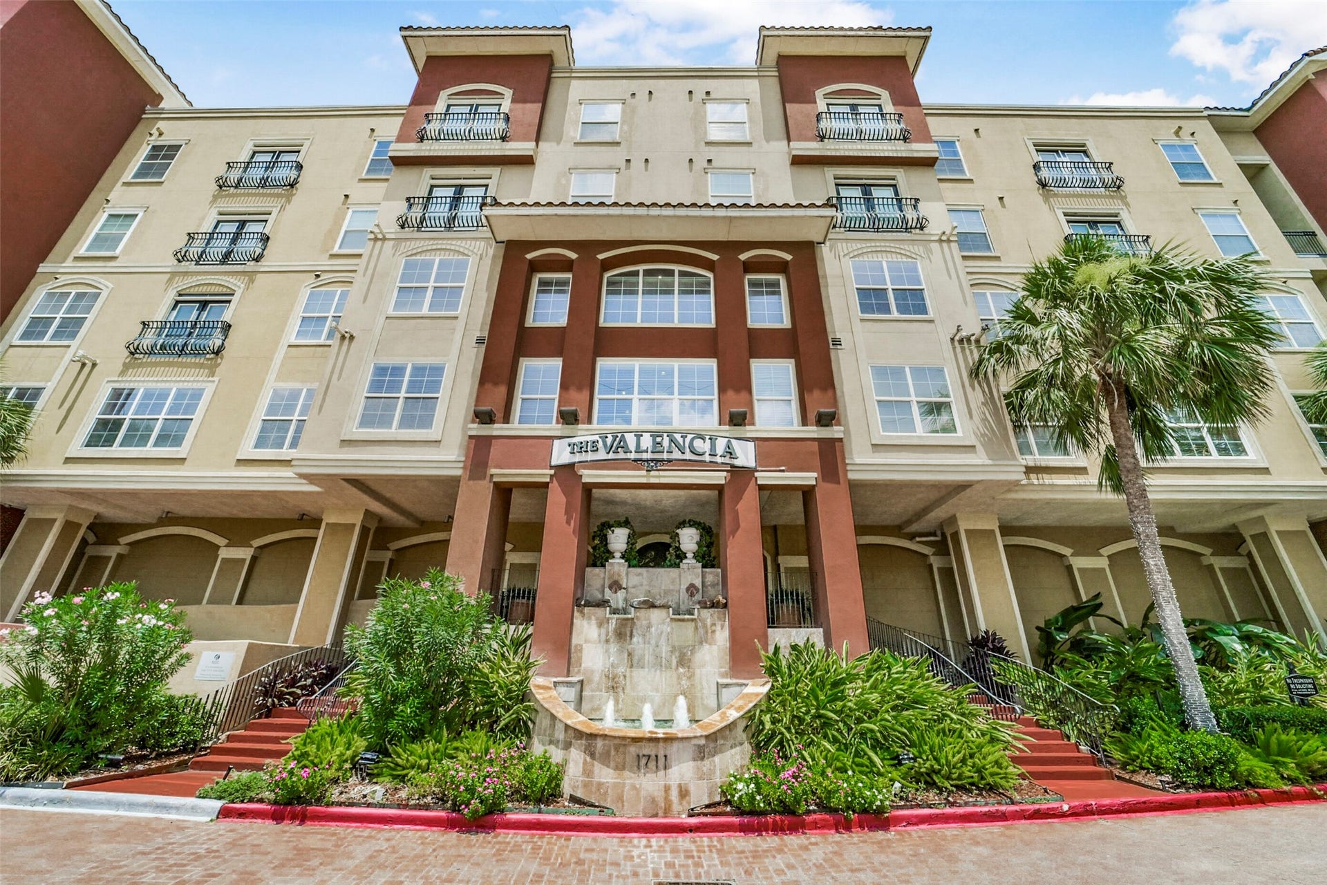 1711 Old Spanish Trail, #437, Houston, TX 77054 Exterior view of The Valencia complex showcasing classic architectural details, exterior lighting, lush landscaping, and water feature.