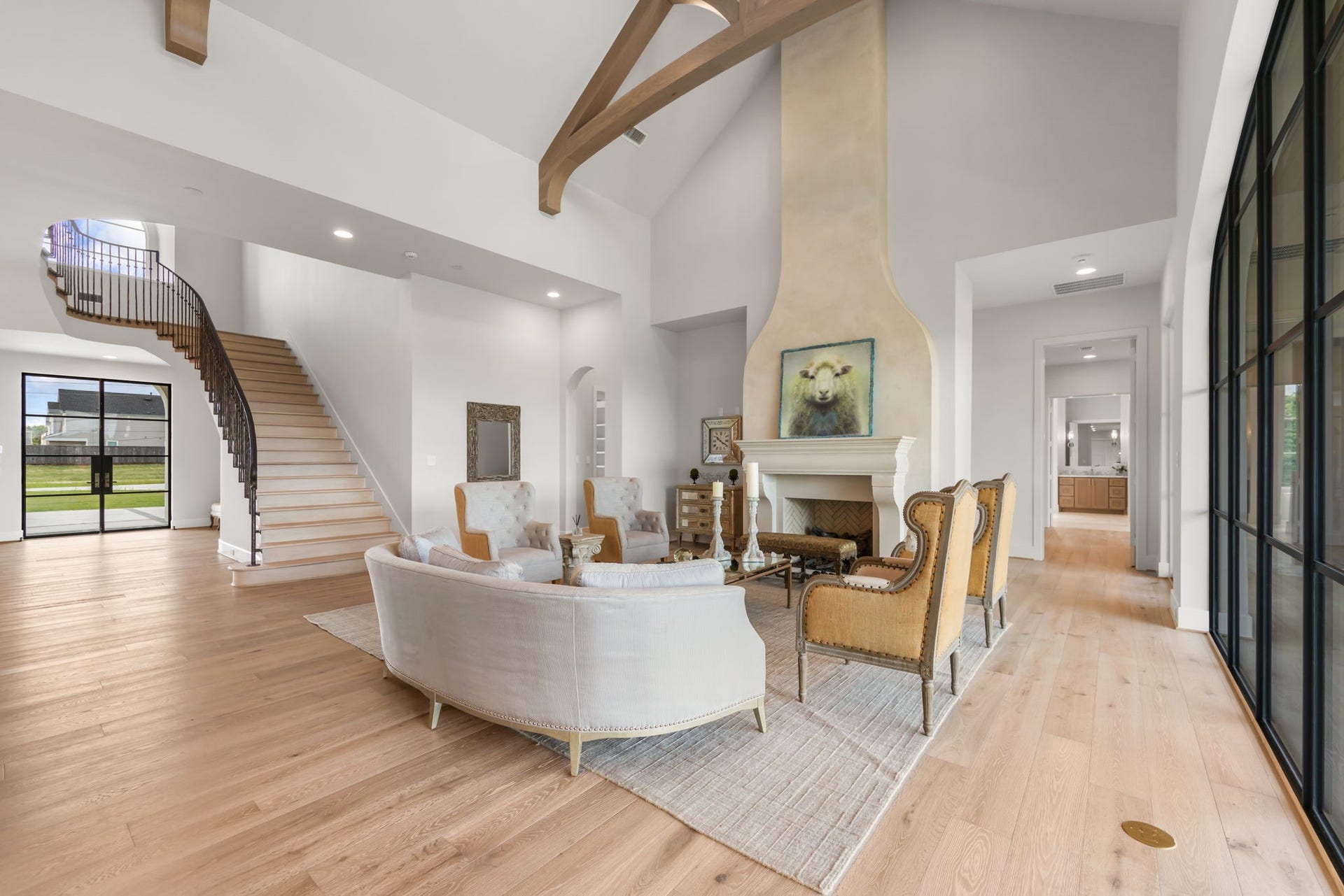 4233 Two Gun Way, Katy, TX 77494 Stunning living room with hardwood floors, floor plugs, cast stone and glazed fireplace with a view of the stunning and sweeping stair case with custom metal banister and large dramatic metal and glass entry doors.