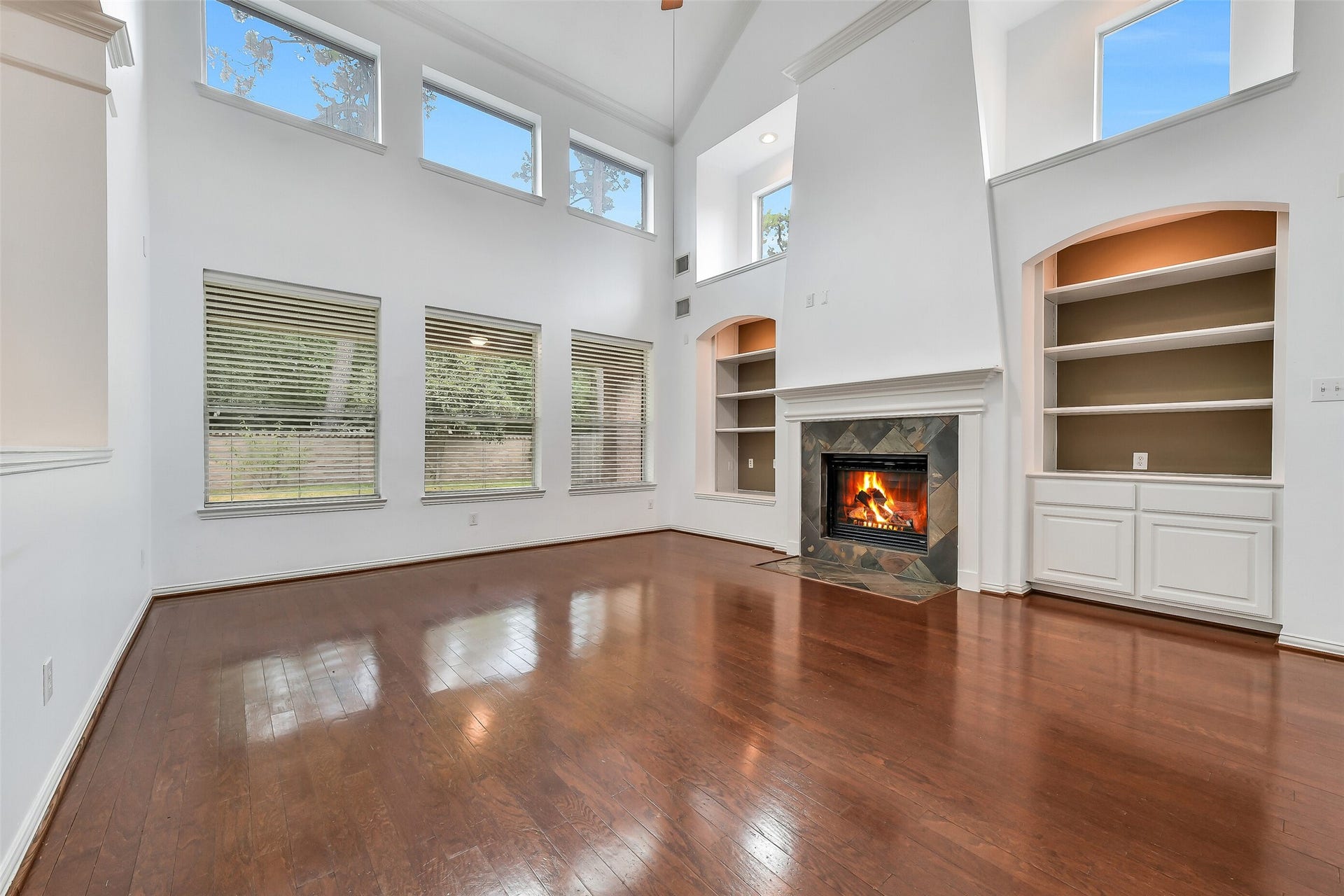 8407 Alyssa Gardens Lane, Humble, TX 77396 The family room boasts soaring ceilings, custom built-in cabinetry, and a gas log fireplace, while ample accent windows fill the space with bright, natural light.