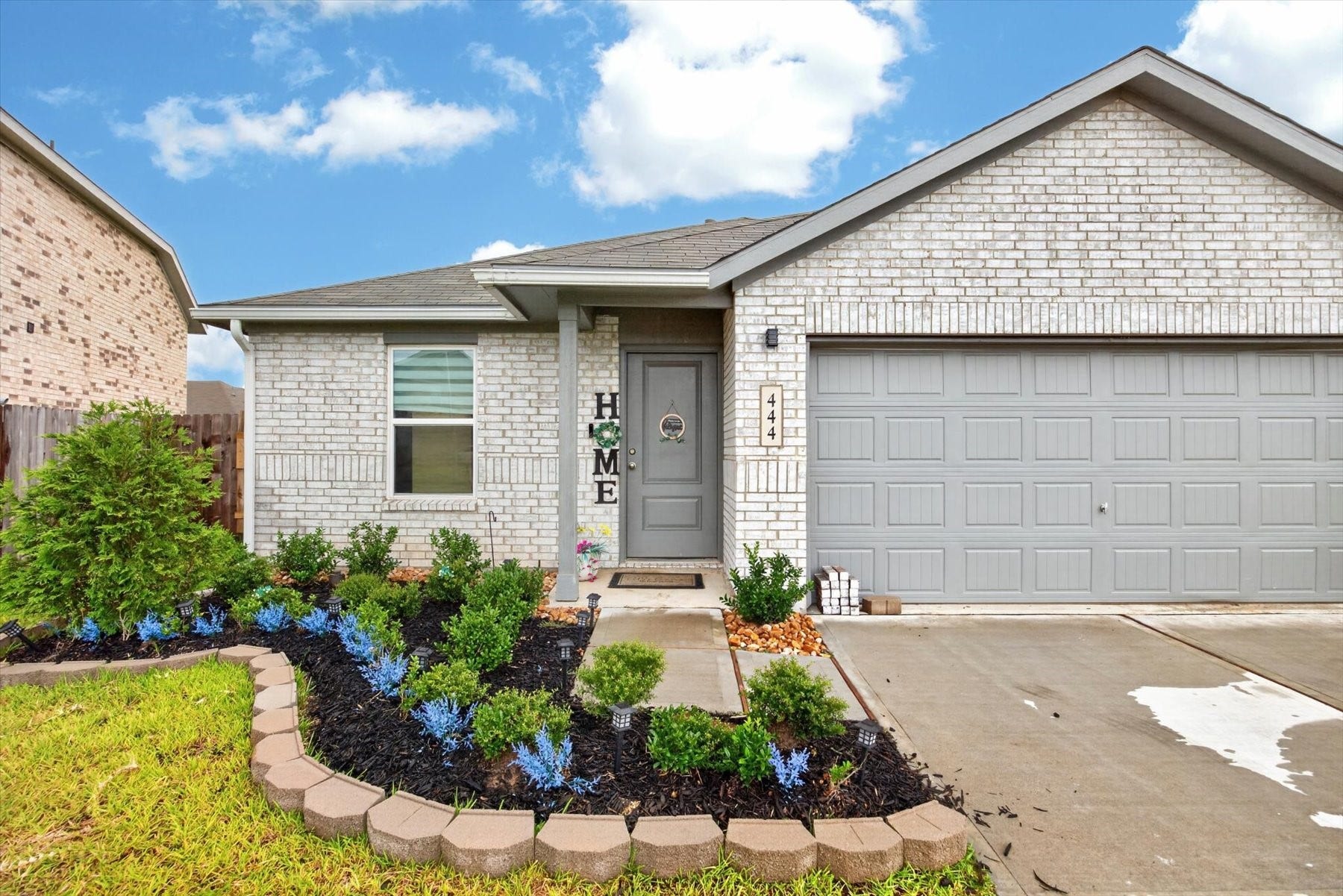 444 Texas Pecan Drive, Katy, TX 77493 Charming single-story home with a modern gray brick exterior and inviting front yard. Features a two-car garage and welcoming entryway, highlighted by a neat walkway and attractive landscaping.