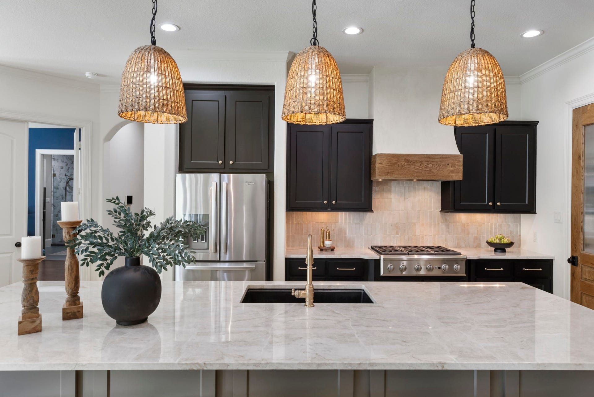 Rich espresso cabinetry, a reclaimed-wood-wrapped vent hood, and handcrafted zellige-style backsplash tile lend artisanal character, paired with stainless appliances for a professional-grade feel.