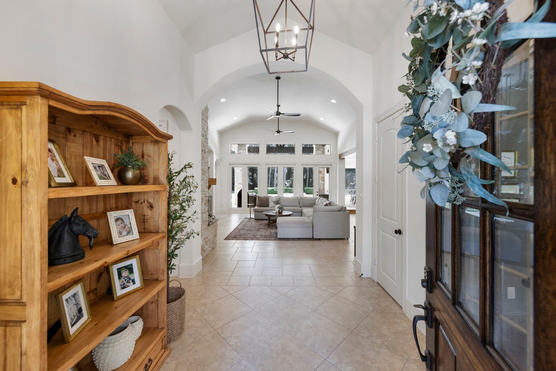 A soaring arched ceiling and wrought lantern chandelier greet you upon entry, with tumbled tile flooring flowing seamlessly toward the great room beyond. Sculptural archways add architectural interest throughout.