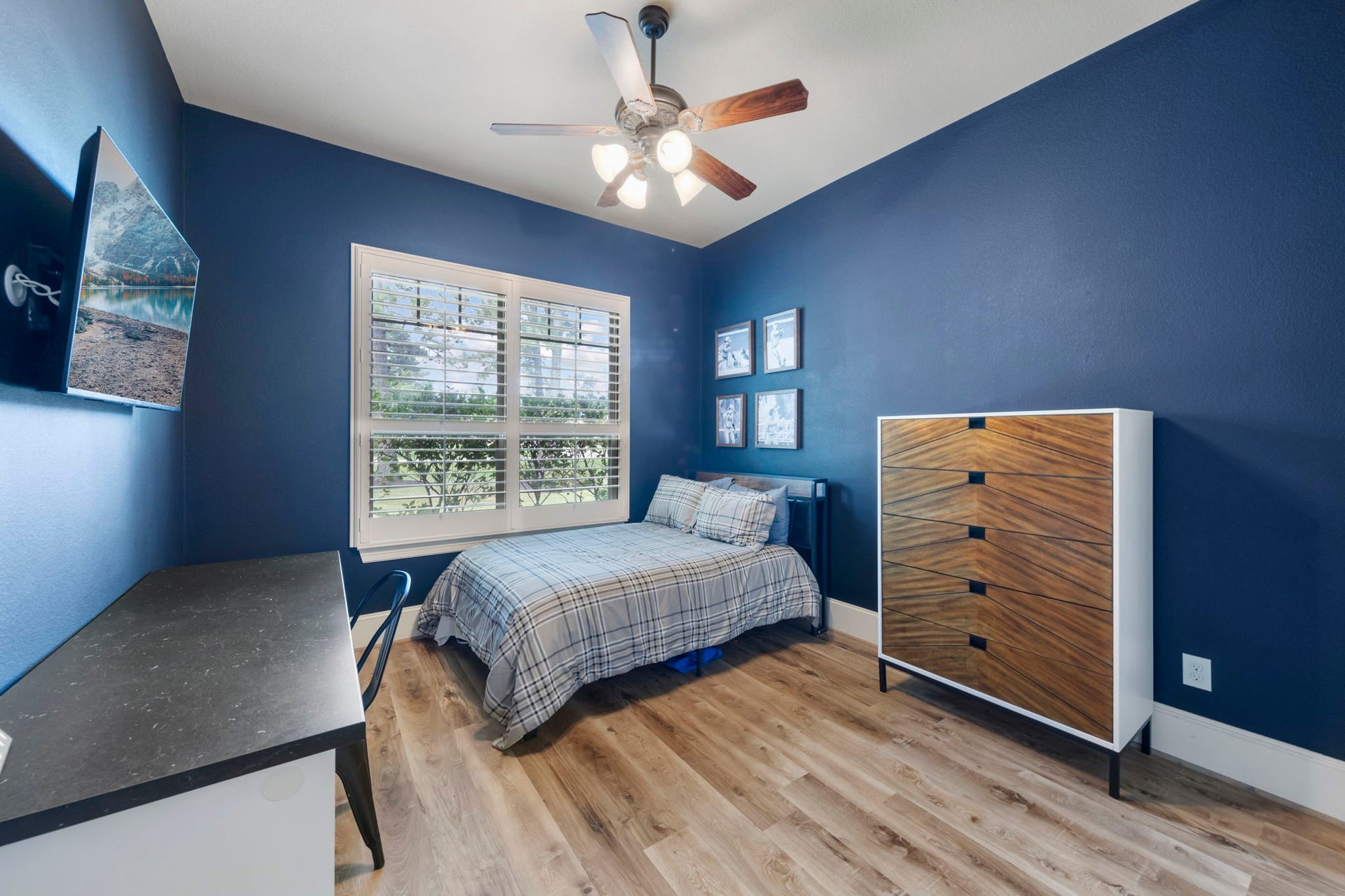 Rich navy walls create a bold, restful backdrop in this secondary bedroom, brightened by a large window overlooking the grounds.