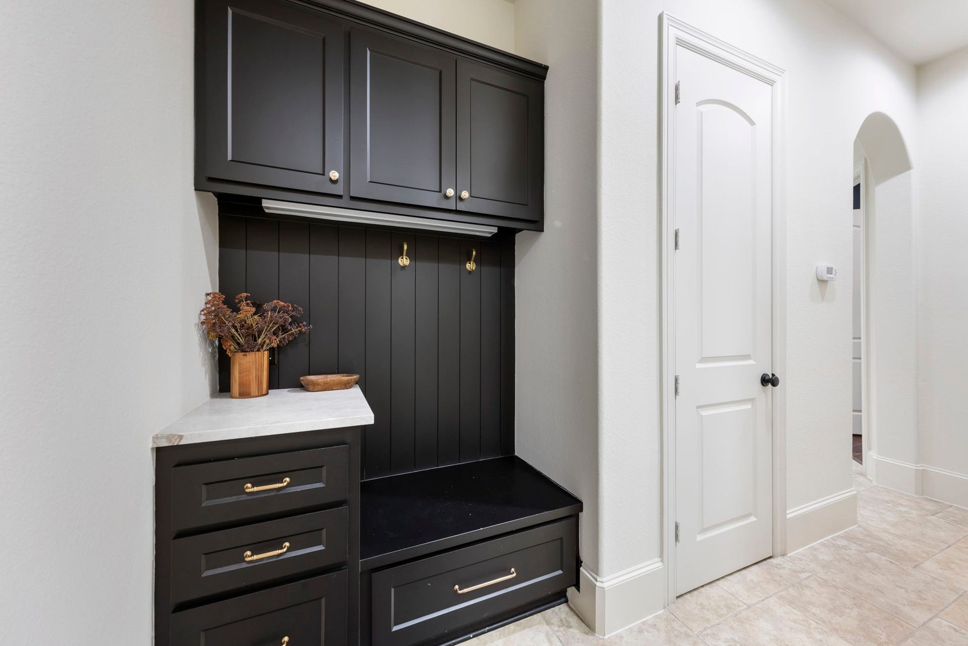 Built-in cabinetry offers a stylish landing spot near the back entry, complete with hooks and marble-topped counter space. Thoughtful design keeps everyday clutter neatly out of sight.