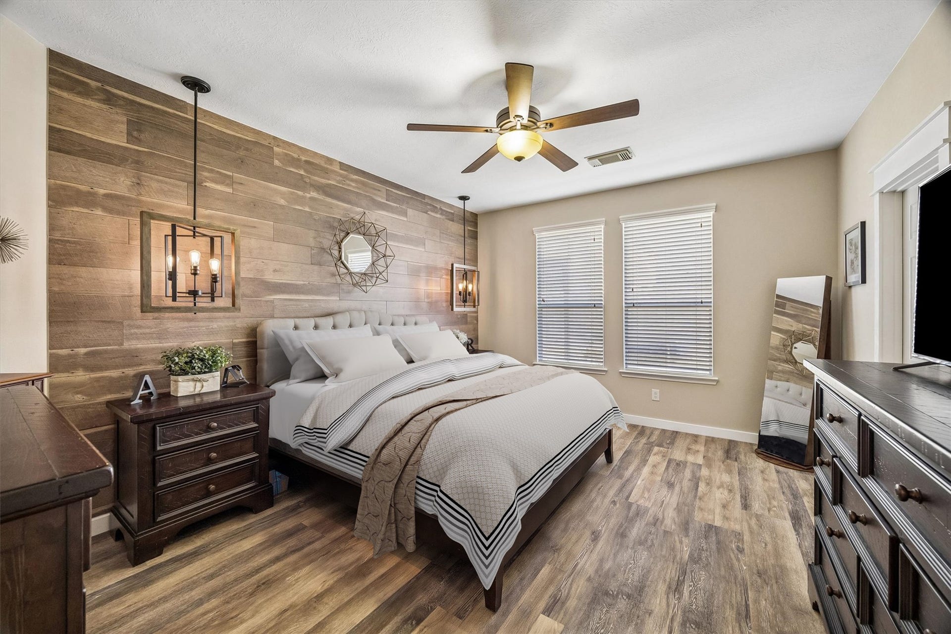 13918 Cypress Creek Bank Drive, Cypress, TX 77429 The primary suite feels warm and inviting, featuring beautiful wood-look flooring, a ceiling fan, and a striking wood accent wall. Generous proportions allow plenty of room for bedroom furnishings.