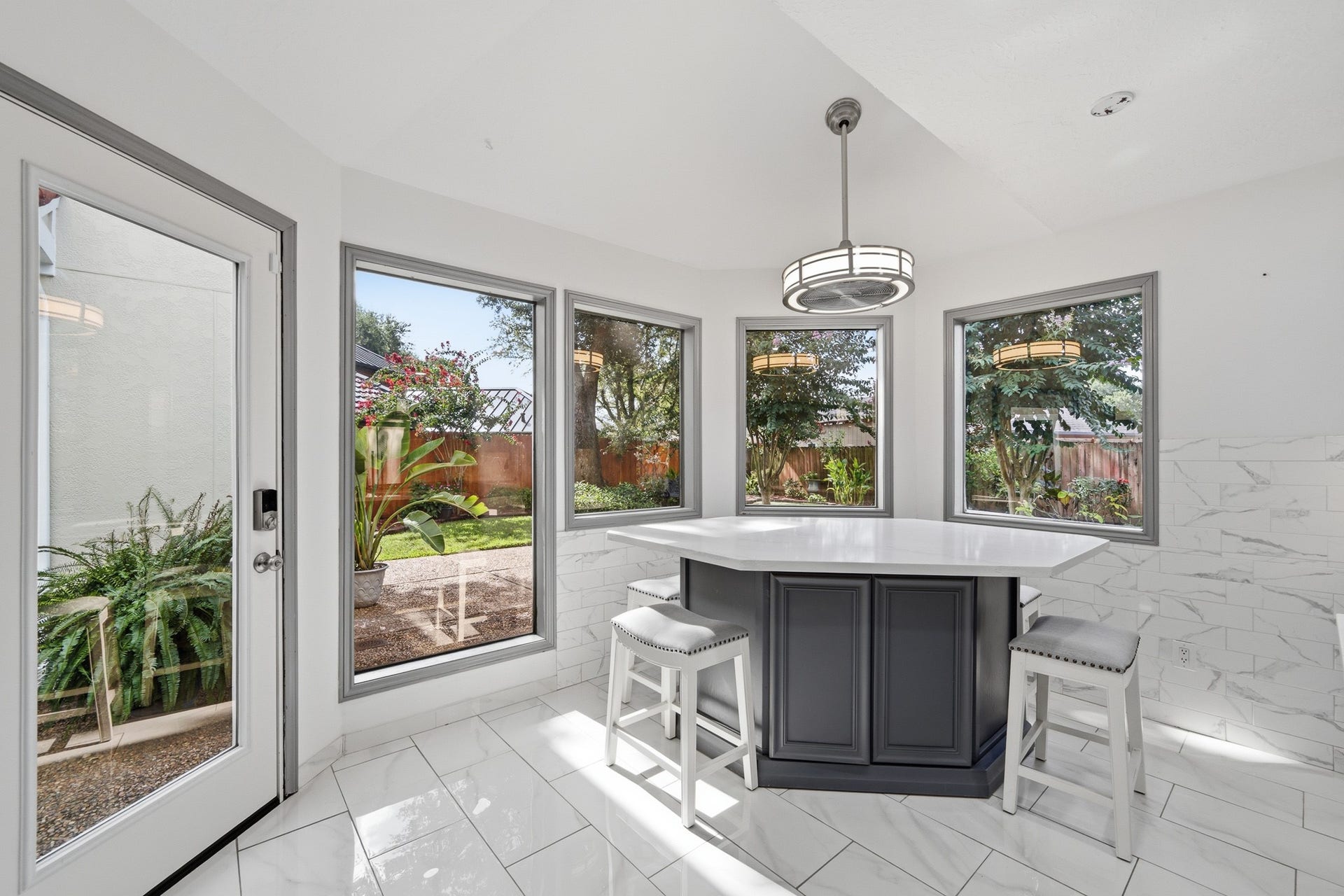 Sun-filled breakfast area surrounded by windows with backyard views, built-in cabinetry, and convenient outdoor access.