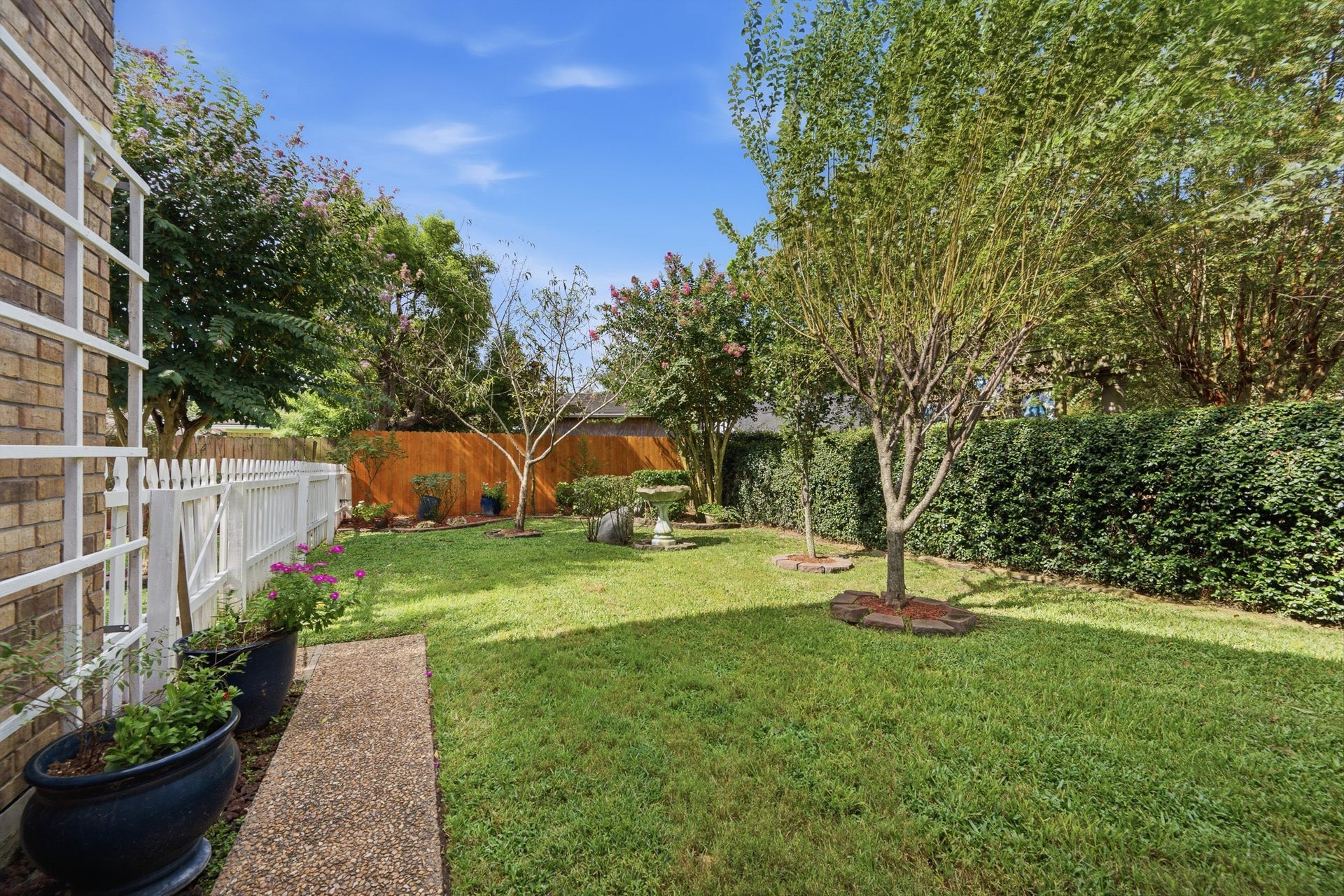 Beautifully landscaped backyard offering privacy, shade, and multiple seating possibilities.