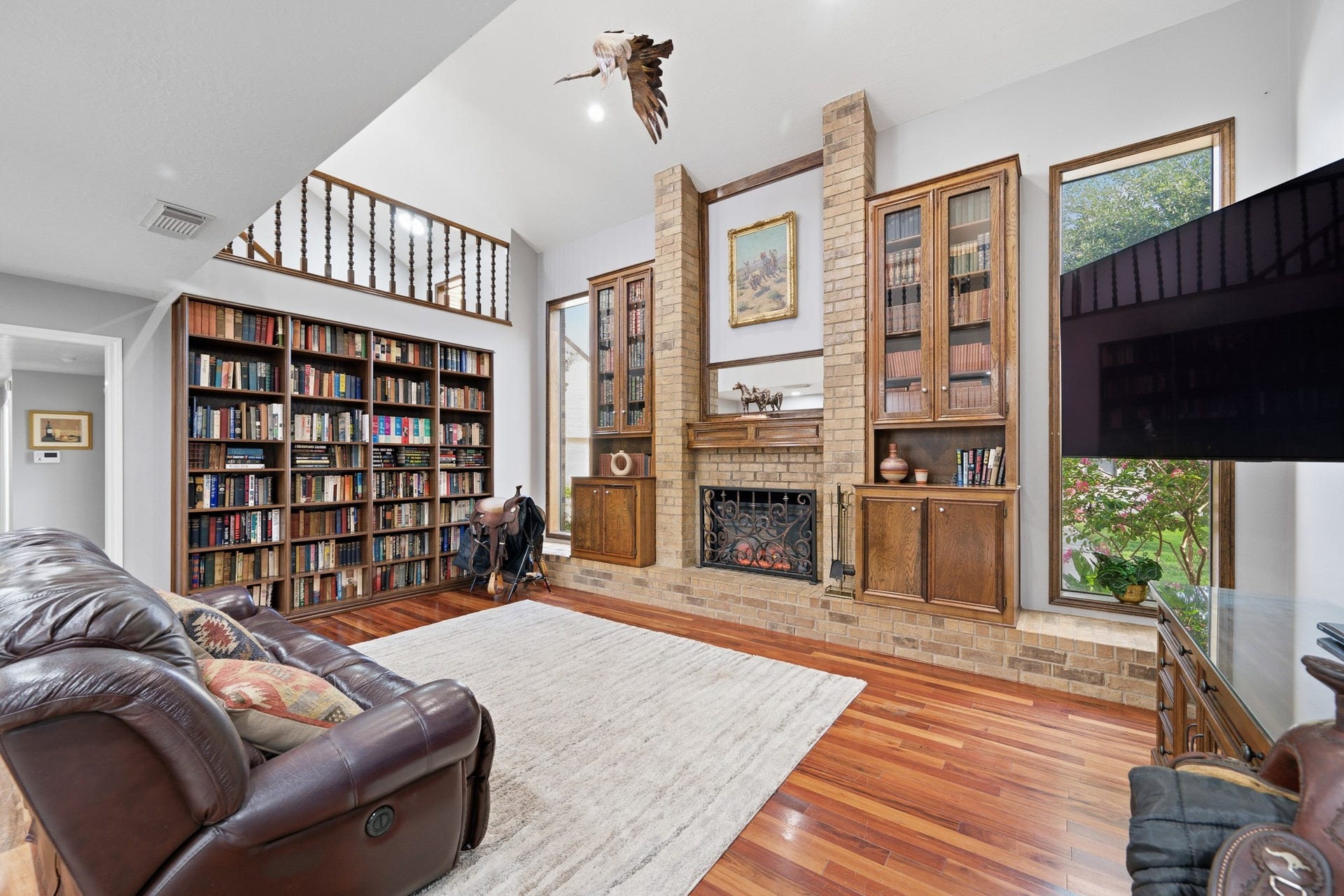 Another view of the spacious living room showcasing the impressive floor-to-ceiling built-ins and open second-story overlook.