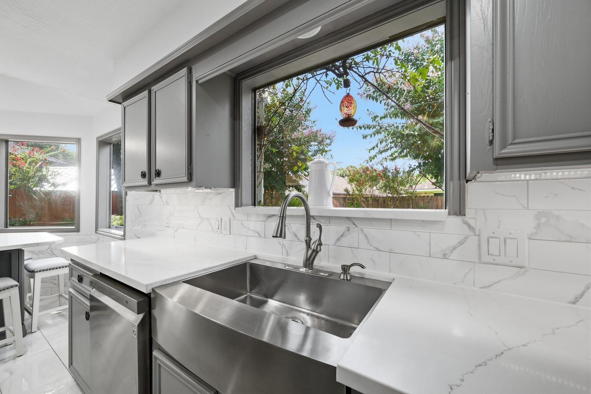 Farmhouse-style stainless steel sink perfectly positioned beneath a large window overlooking the backyard.