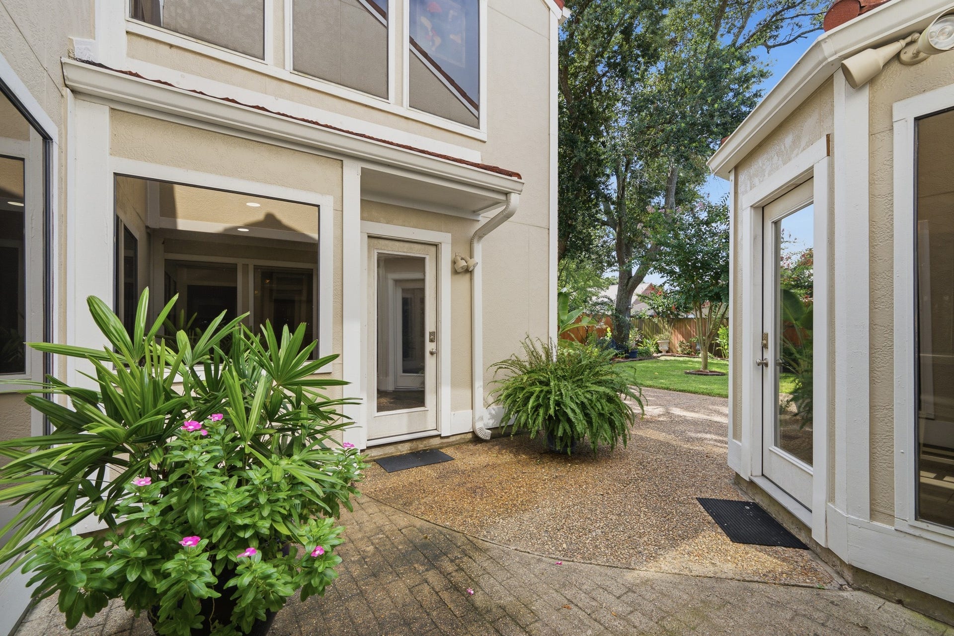 Charming private courtyard surrounded by mature landscaping and multiple windows.
