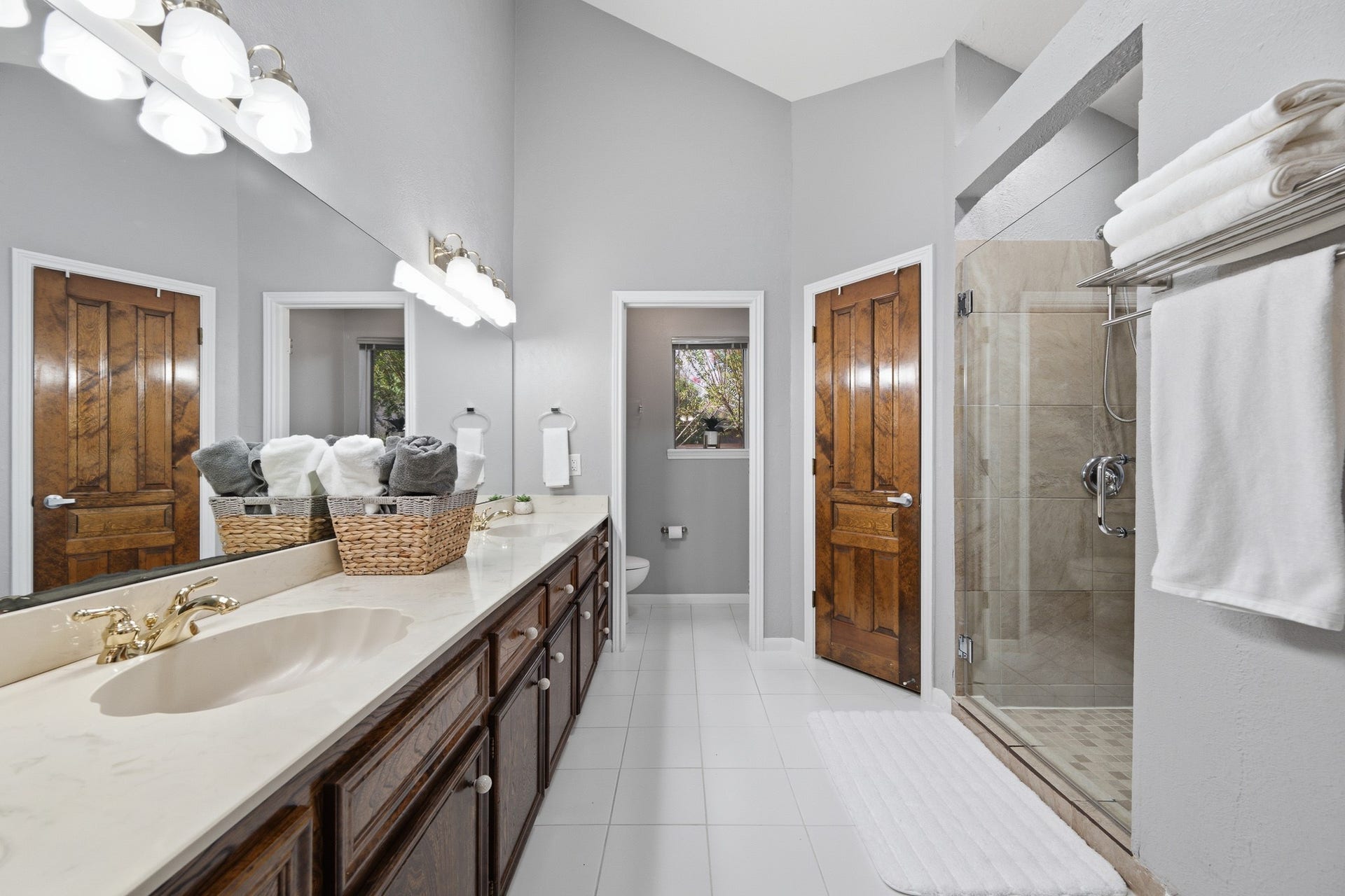 Bright bathroom with an extended vanity, generous storage, and a glass-enclosed shower.