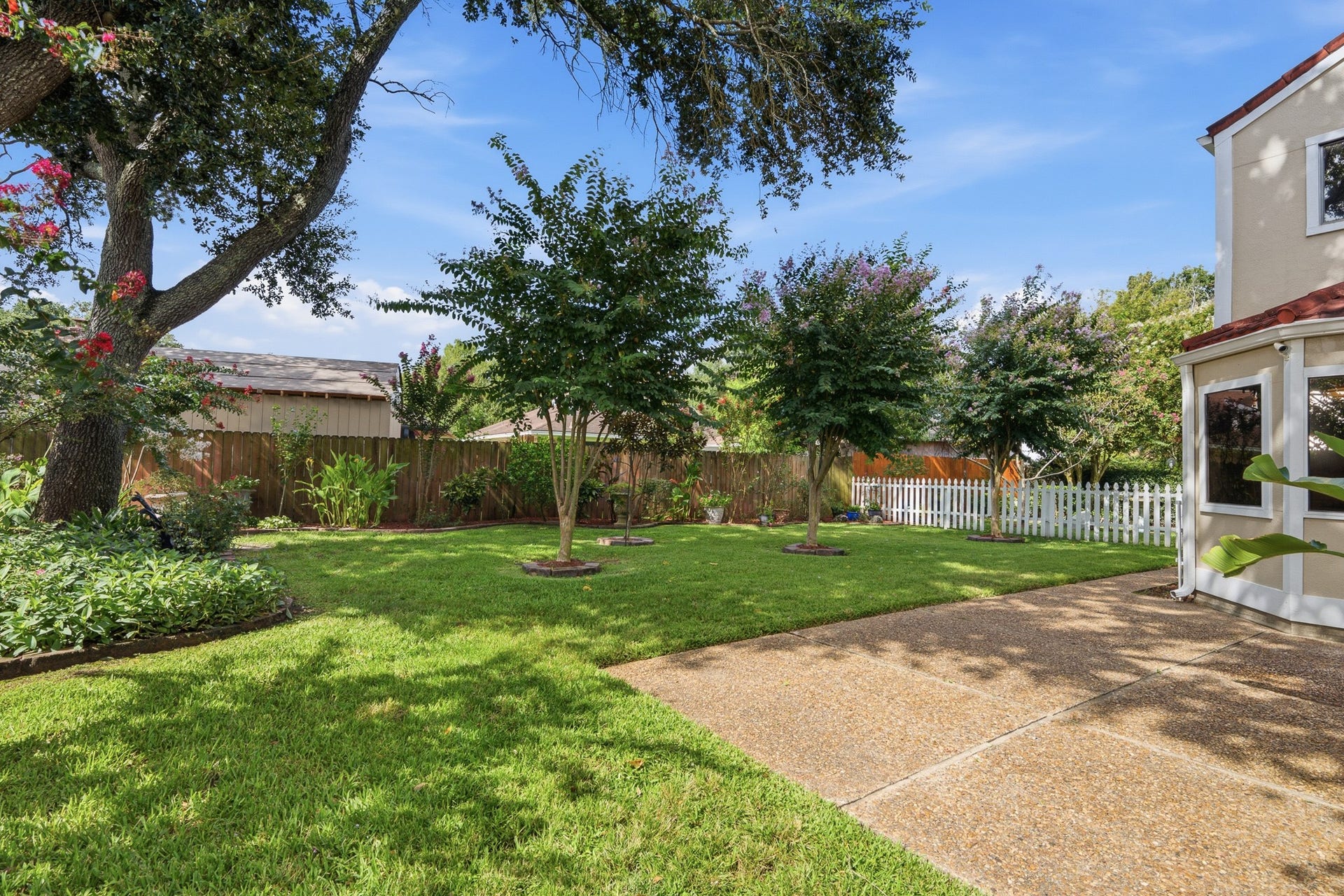 Spacious backyard with mature trees, lush lawn, and plenty of room for outdoor activities.