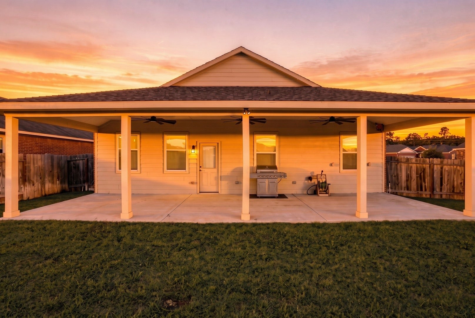 18042 Atwood Mill Drive, New Caney, TX 77357 Twilight view showcasing the expansive covered patio and backyardan inviting outdoor space for relaxing or entertaining in the evenings. Virtual grass enhancement and sunset