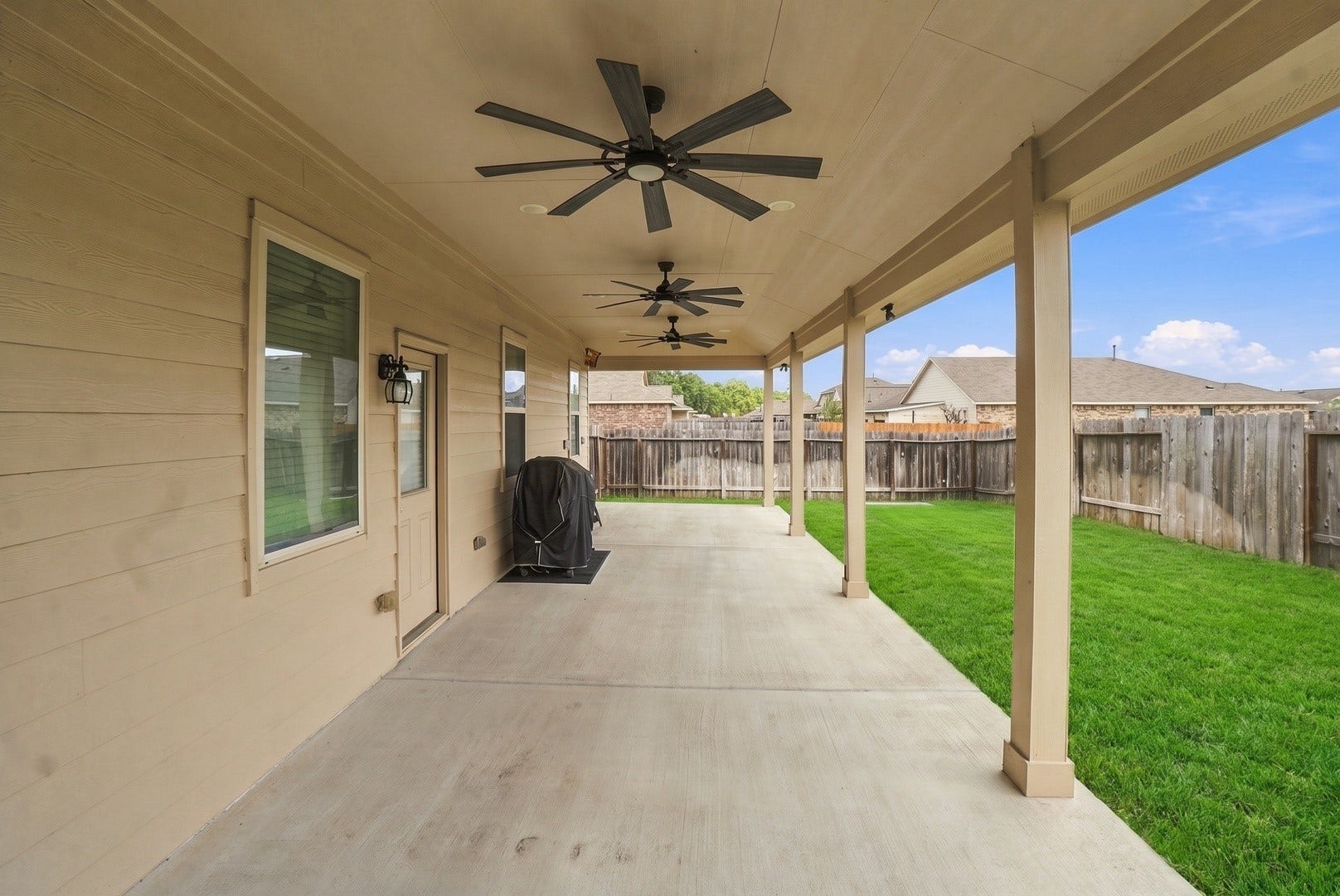 18042 Atwood Mill Drive, New Caney, TX 77357 View from beneath the covered patio highlights the generous amount of usable outdoor living space, multiple ceiling fans, and direct access to the backyard.