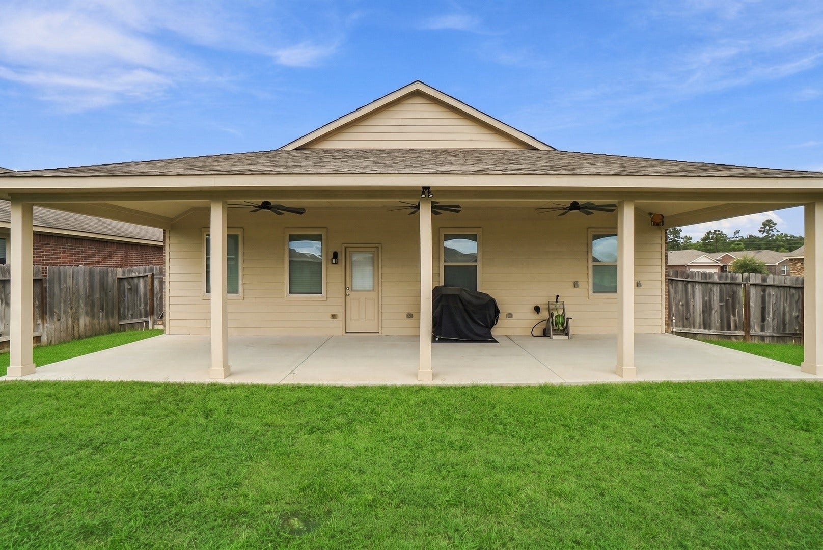 18042 Atwood Mill Drive, New Caney, TX 77357 Full view of the homes impressive covered back patio spanning much of the rear exterior, overlooking the fenced backyard.