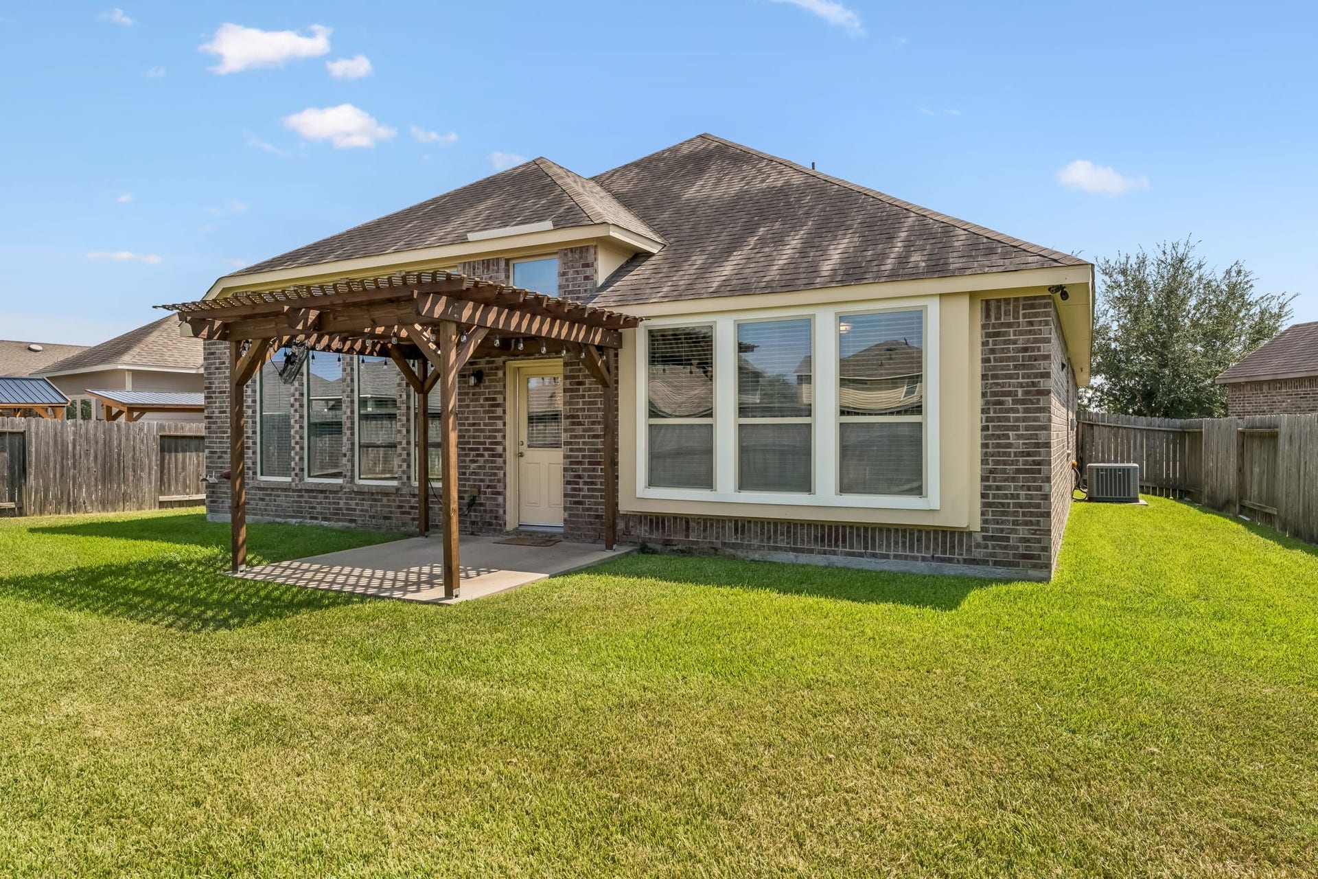 5107 Baroness Lane, Katy, TX 77493 Charming brick home with a spacious backyard, featuring a lovely pergola-covered patio perfect for outdoor relaxation.
