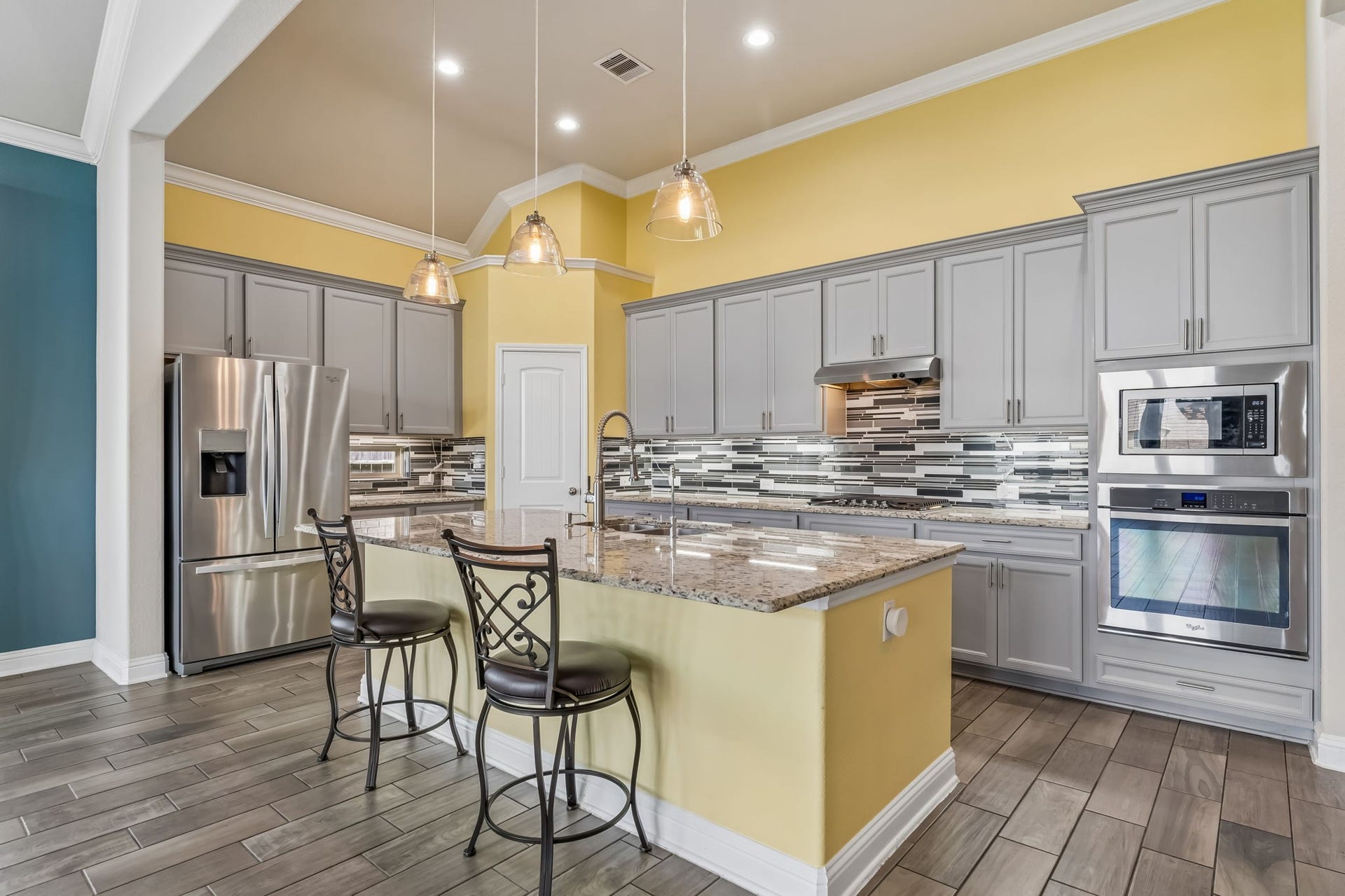 5107 Baroness Lane, Katy, TX 77493 Bright and modern kitchen with sleek gray cabinetry, stainless steel appliances, and a stylish mosaic backsplash. The spacious island provides ample workspace and seating, perfect for entertaining.