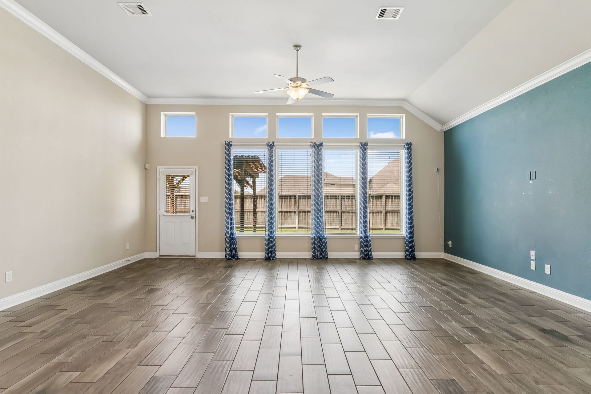 5107 Baroness Lane, Katy, TX 77493 Spacious living area with high ceilings, large windows for natural light, and elegant wood-look tile flooring.