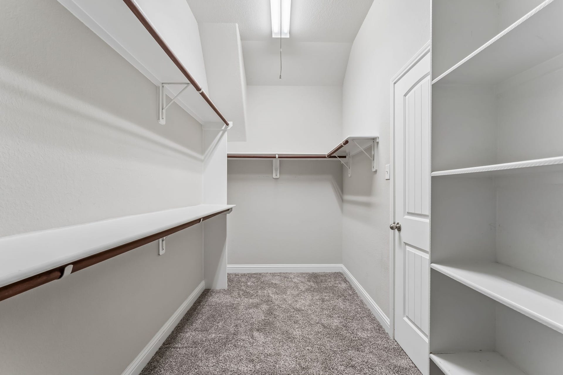 5107 Baroness Lane, Katy, TX 77493 Spacious walk-in closet featuring ample shelving and hanging space, complemented by plush carpeting and bright lighting.