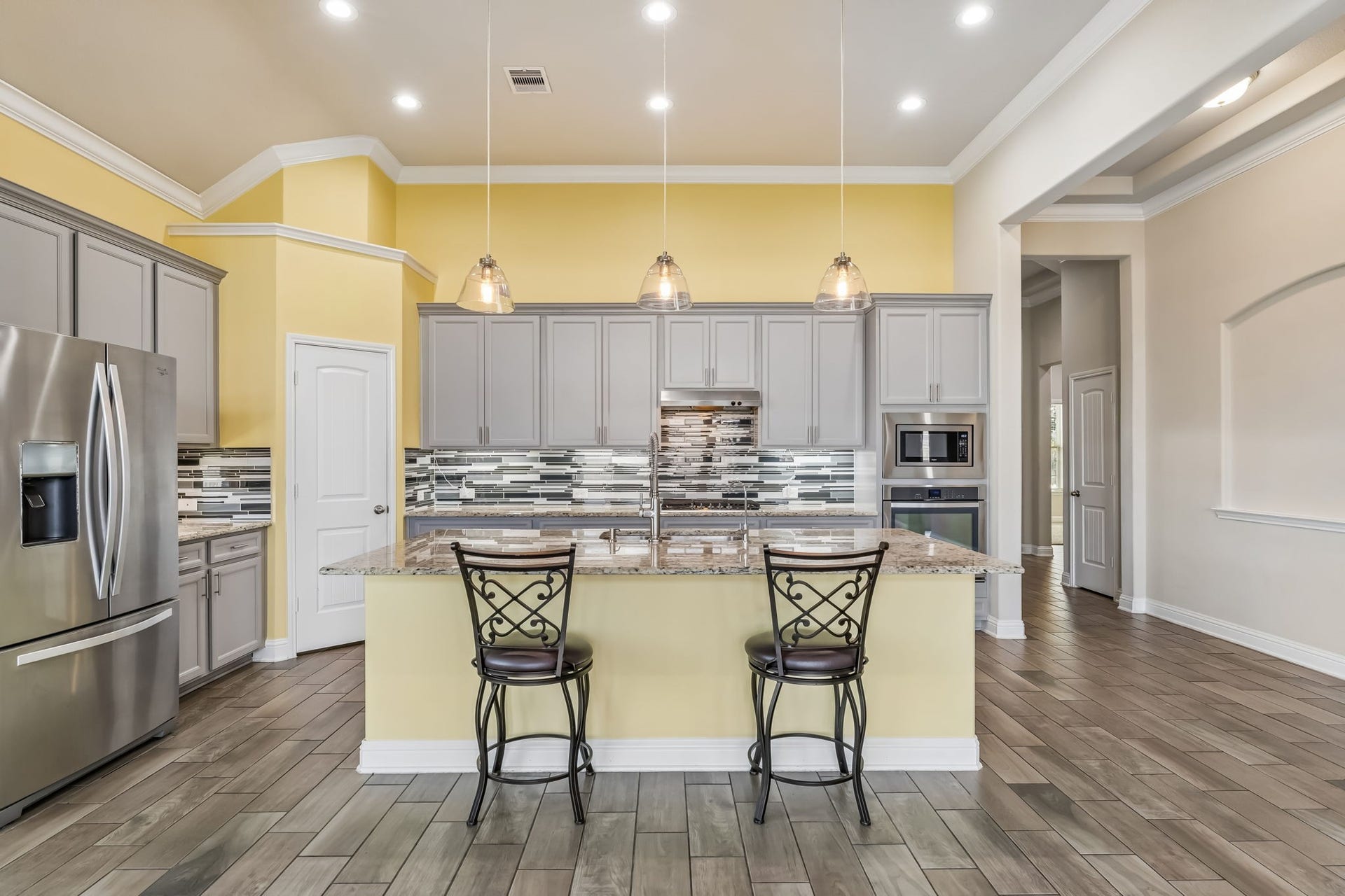 5107 Baroness Lane, Katy, TX 77493 Elegant kitchen with modern stainless steel appliances, a spacious island with seating, and stylish pendant lighting. The sleek backsplash and warm color palette create a welcoming atmosphere.