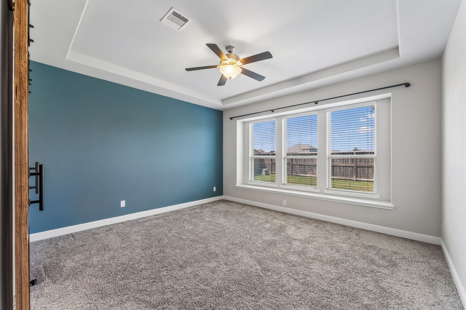 5107 Baroness Lane, Katy, TX 77493 Spacious primary bedroom featuring a soothing blue accent wall, plush carpeting, and large windows that provide abundant natural light.