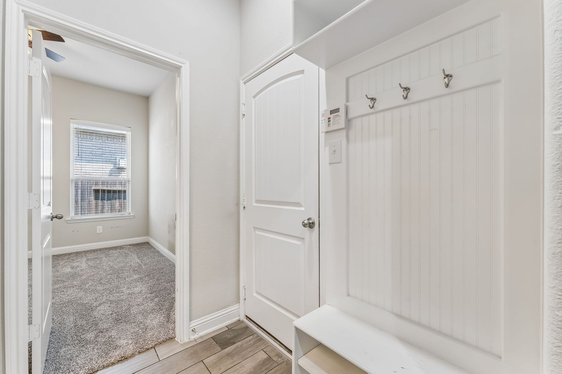 5107 Baroness Lane, Katy, TX 77493 Charming entryway features a practical mudroom area with hooks and storage, leading into a cozy, carpeted room with a large window for natural light.