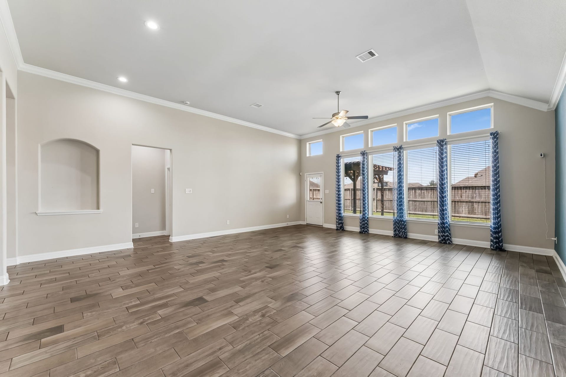 5107 Baroness Lane, Katy, TX 77493 Spacious living area with high ceilings, abundant natural light from large windows, elegant tile flooring, and a ceiling fan for added comfort.