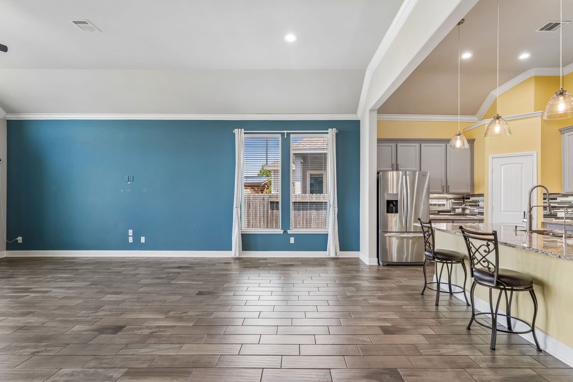 5107 Baroness Lane, Katy, TX 77493 Spacious open-concept living area with elegant tile flooring, vibrant accent wall, and a modern kitchen featuring stainless steel appliances and a large breakfast bar.