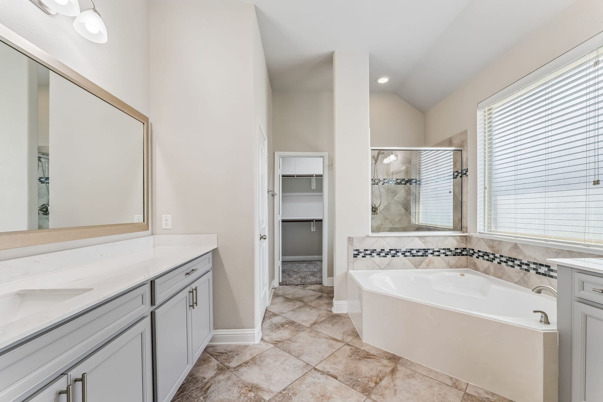 5107 Baroness Lane, Katy, TX 77493 Elegant bathroom featuring a spacious soaking tub, dual sinks with stylish cabinetry, and a walk-in closet, all accentuated by natural light.