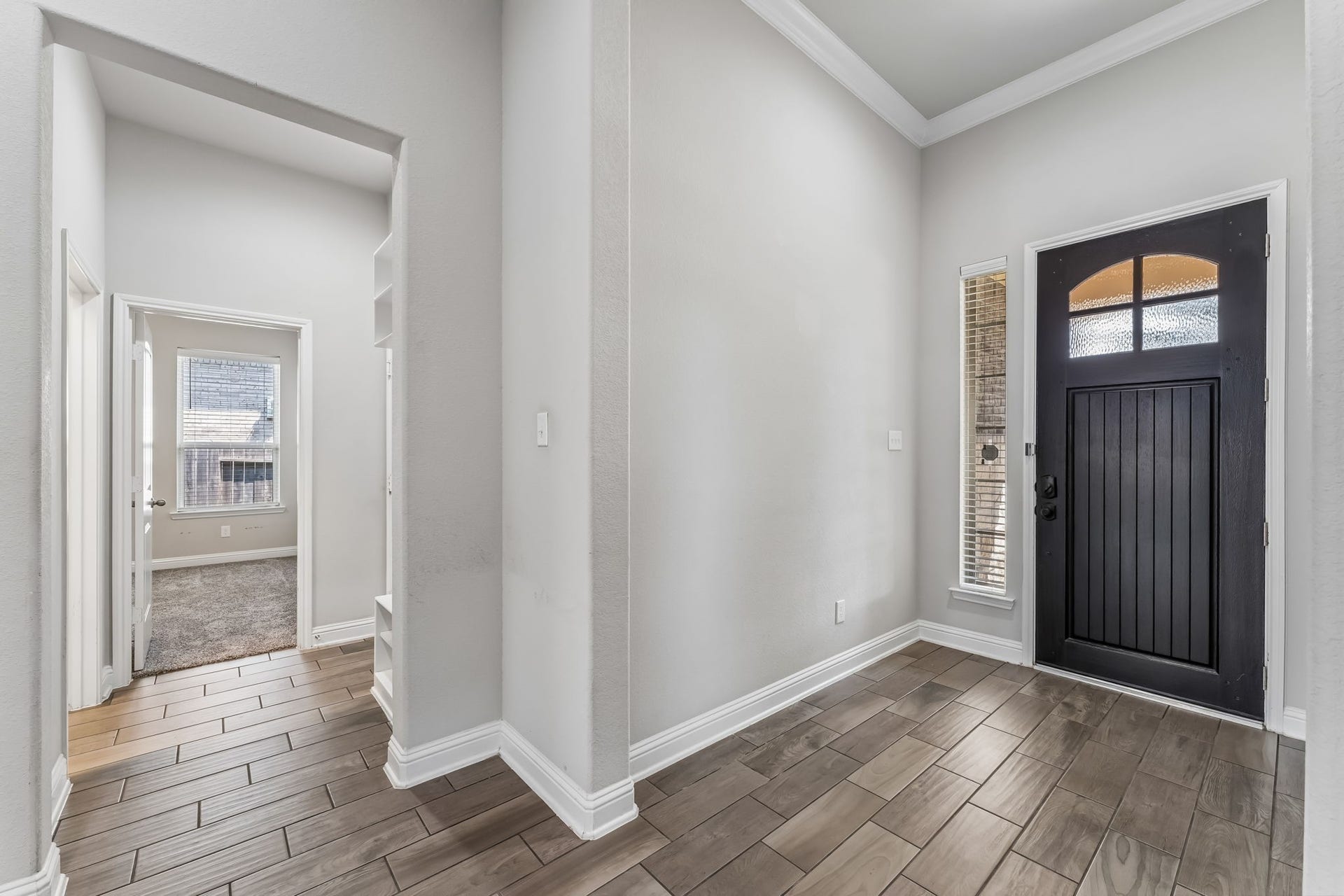 5107 Baroness Lane, Katy, TX 77493 Inviting entryway featuring a dark wood front door, elegant tile flooring, and abundant natural light from tall windows, leading seamlessly to the rest of the home.