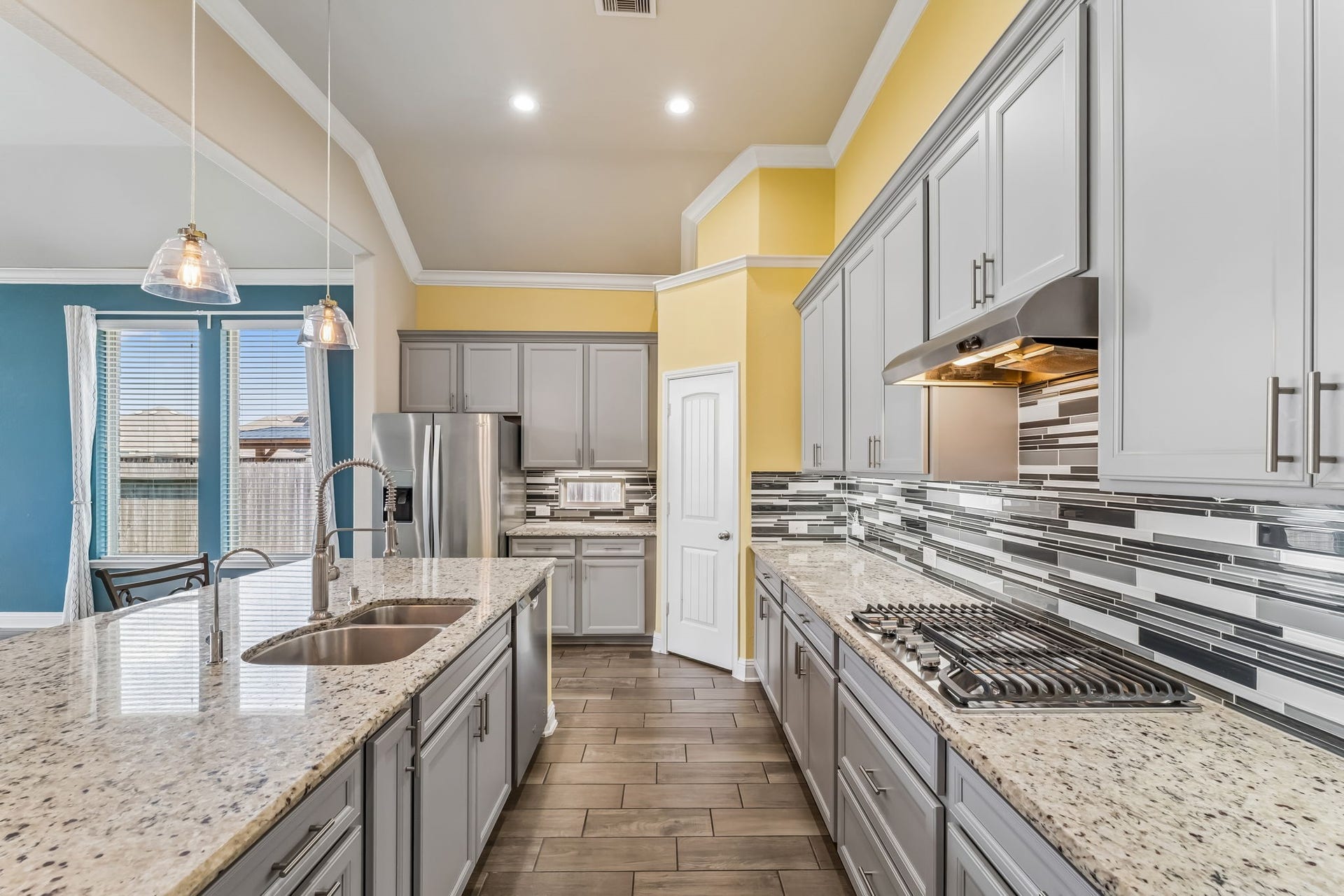 5107 Baroness Lane, Katy, TX 77493 Spacious kitchen with granite countertops, modern stainless steel appliances, and elegant pendant lighting, complemented by stylish cabinetry and a chic tile backsplash.