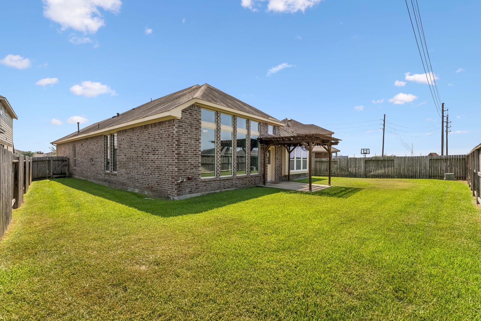 5107 Baroness Lane, Katy, TX 77493 Expansive backyard with a charming pergola, perfect for outdoor gatherings, complemented by a well-maintained lawn and a privacy fence.