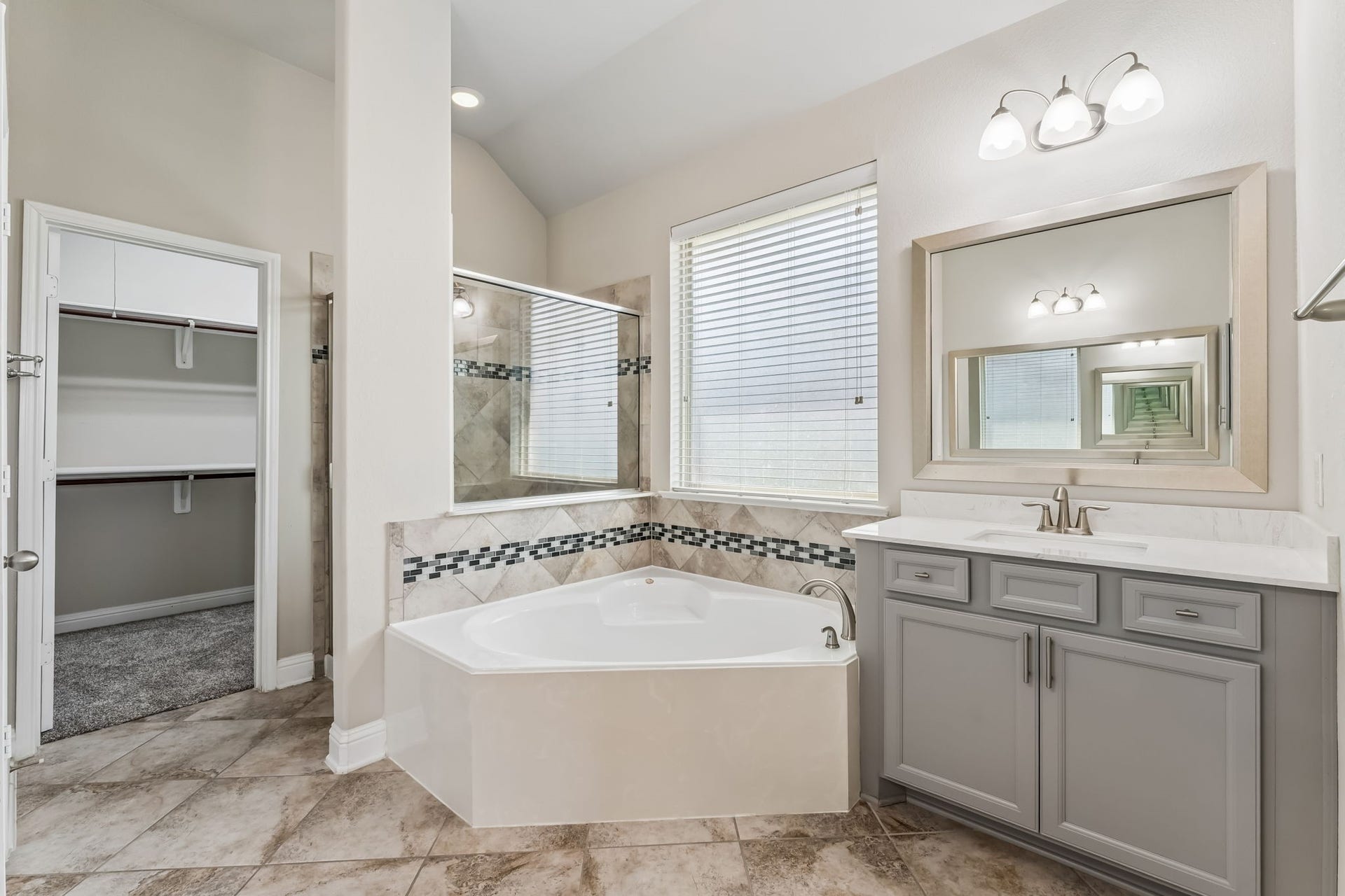 5107 Baroness Lane, Katy, TX 77493 Elegant bathroom with a luxurious soaking tub, dual sinks, and stylish tile accents. Ample natural light enhances the spacious feel, and the walk-in closet offers convenient storage.