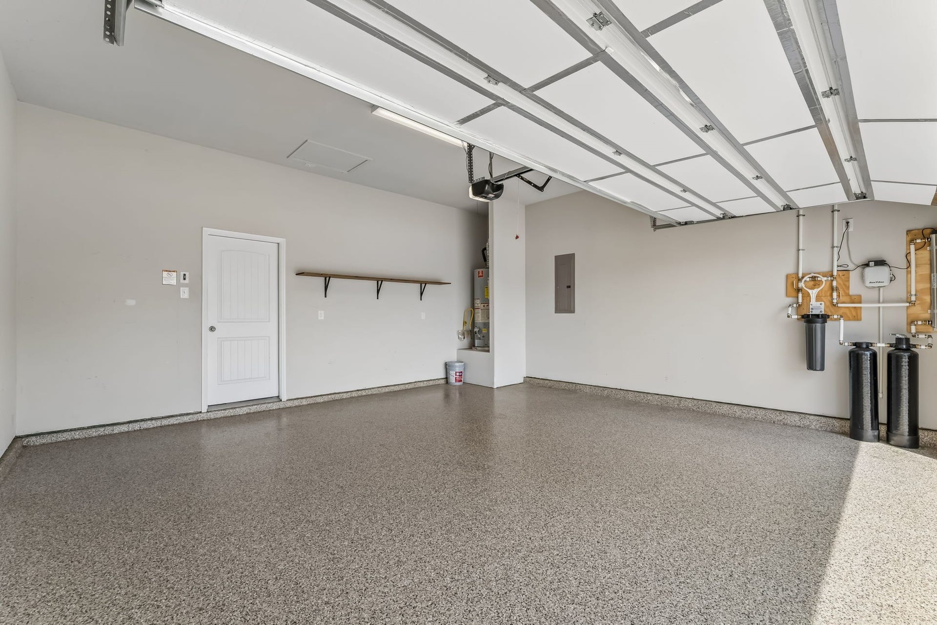 5107 Baroness Lane, Katy, TX 77493 Spacious garage with a sleek epoxy floor, built-in storage shelf, modern utility systems, and epoxy flooring, perfect for organization and functionality.