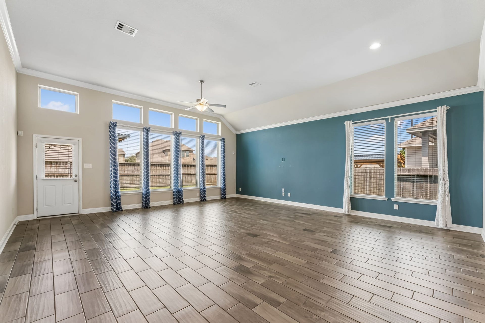5107 Baroness Lane, Katy, TX 77493 Spacious living area with high ceilings, large windows for natural light, and stylish wood-look tile flooring, perfect for entertaining and relaxation.