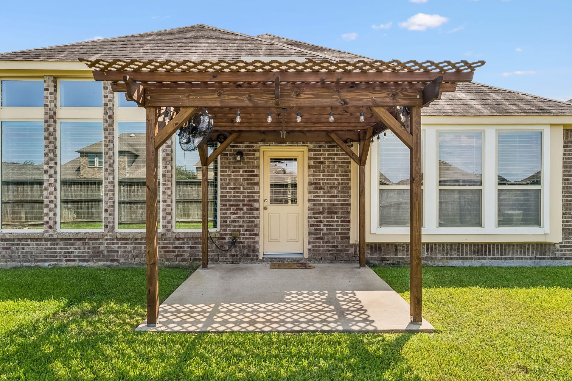 5107 Baroness Lane, Katy, TX 77493 Charming backyard features a cozy pergola-covered patio, perfect for outdoor relaxation and entertaining, set against a backdrop of large windows that invite natural light into the home.