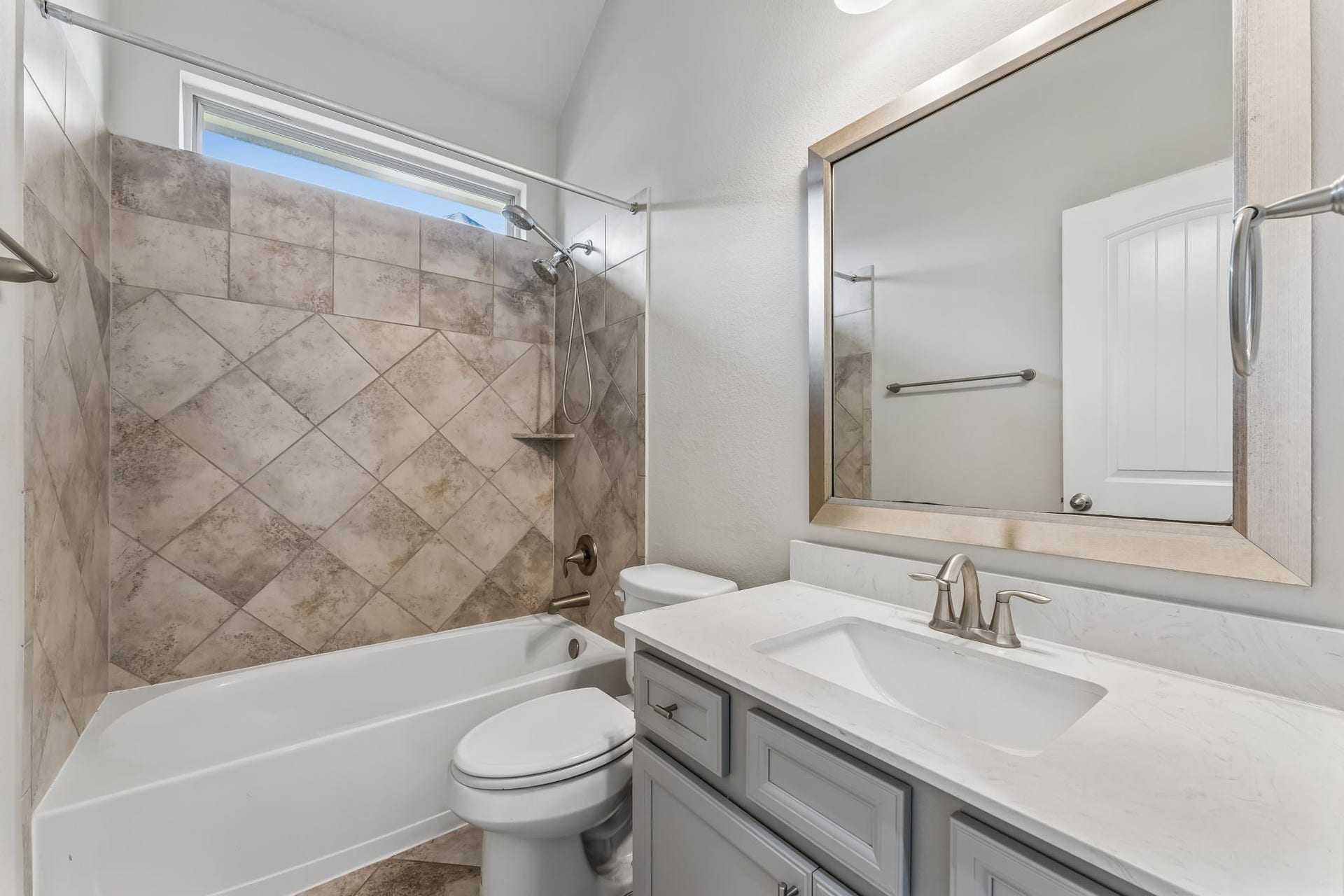 5107 Baroness Lane, Katy, TX 77493 Charming bathroom featuring a tiled shower-bath combo, a sleek vanity with a modern faucet, and a large framed mirror.