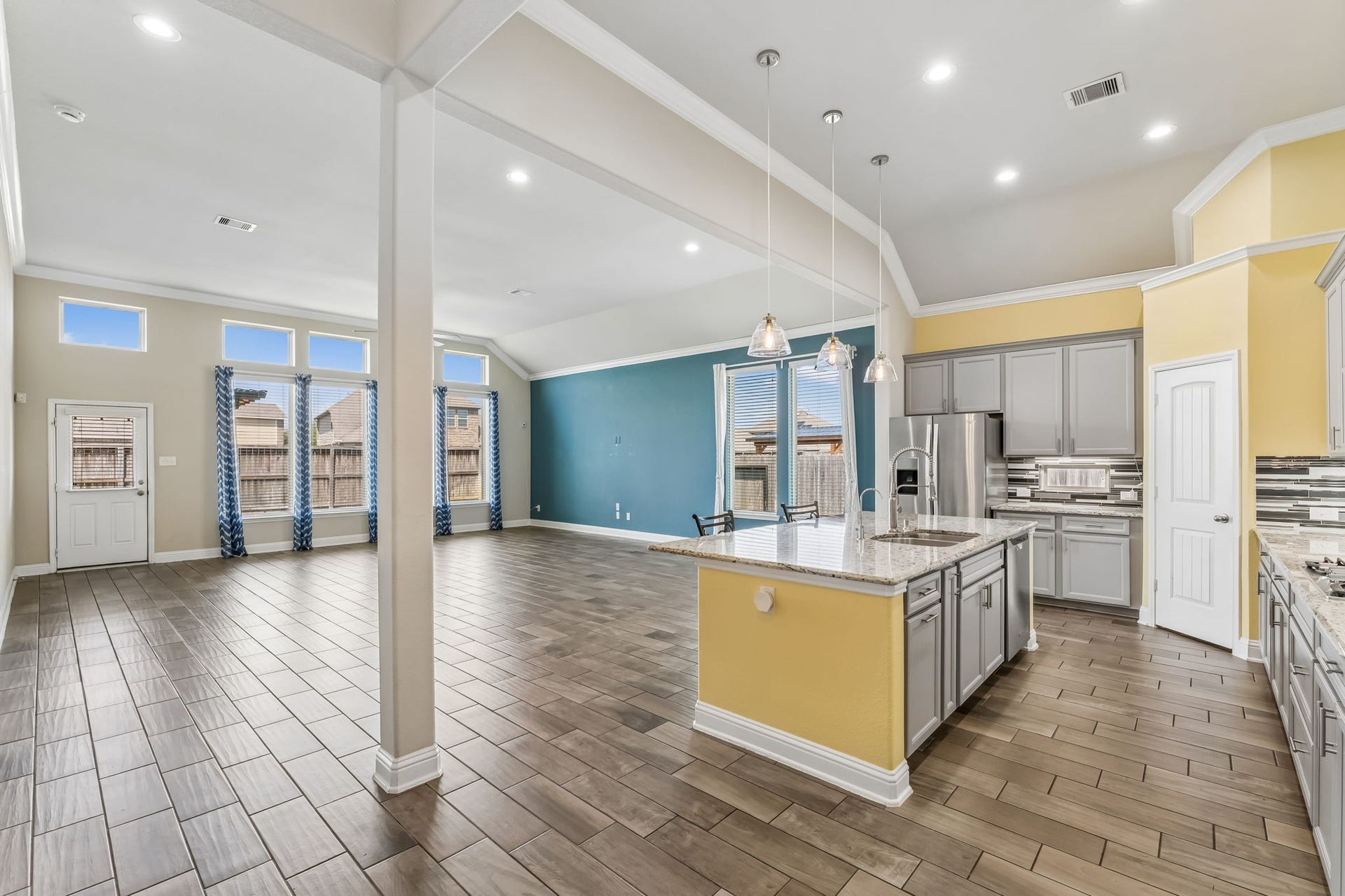 5107 Baroness Lane, Katy, TX 77493 Open-concept living area with high ceilings, abundant natural light, and a modern kitchen featuring an island and stainless steel appliances.