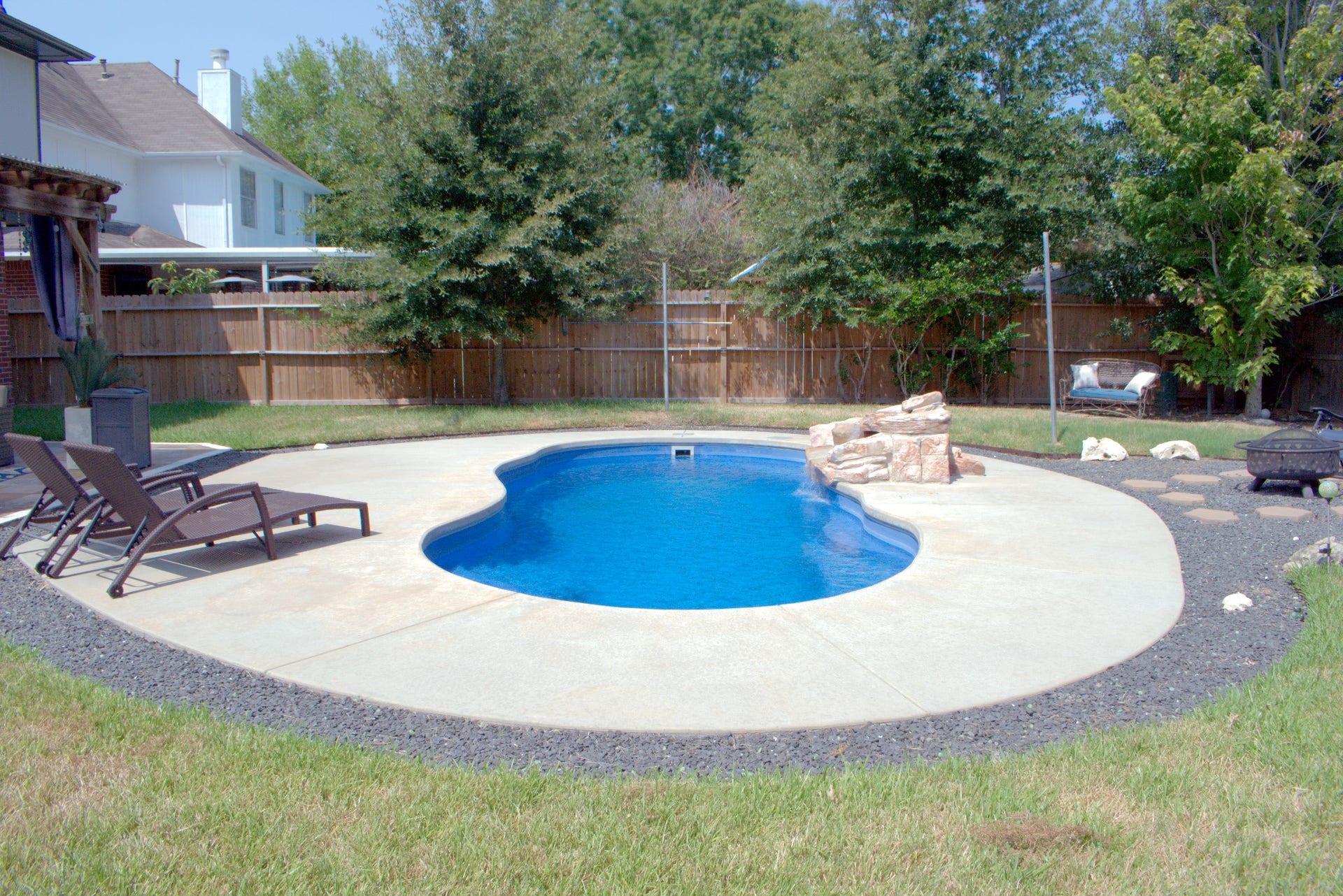 22510 Rangeview Drive, Katy, TX 77450 Relax in a backyard oasis featuring a sparkling kidney-shaped pool, surrounded by lush greenery and a cozy seating area perfect for outdoor enjoyment.