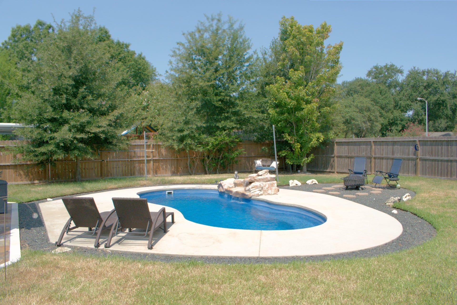 22510 Rangeview Drive, Katy, TX 77450 Charming backyard oasis featuring a sparkling in-ground pool with a stone accent, surrounded by lush greenery and ample seating for relaxation.