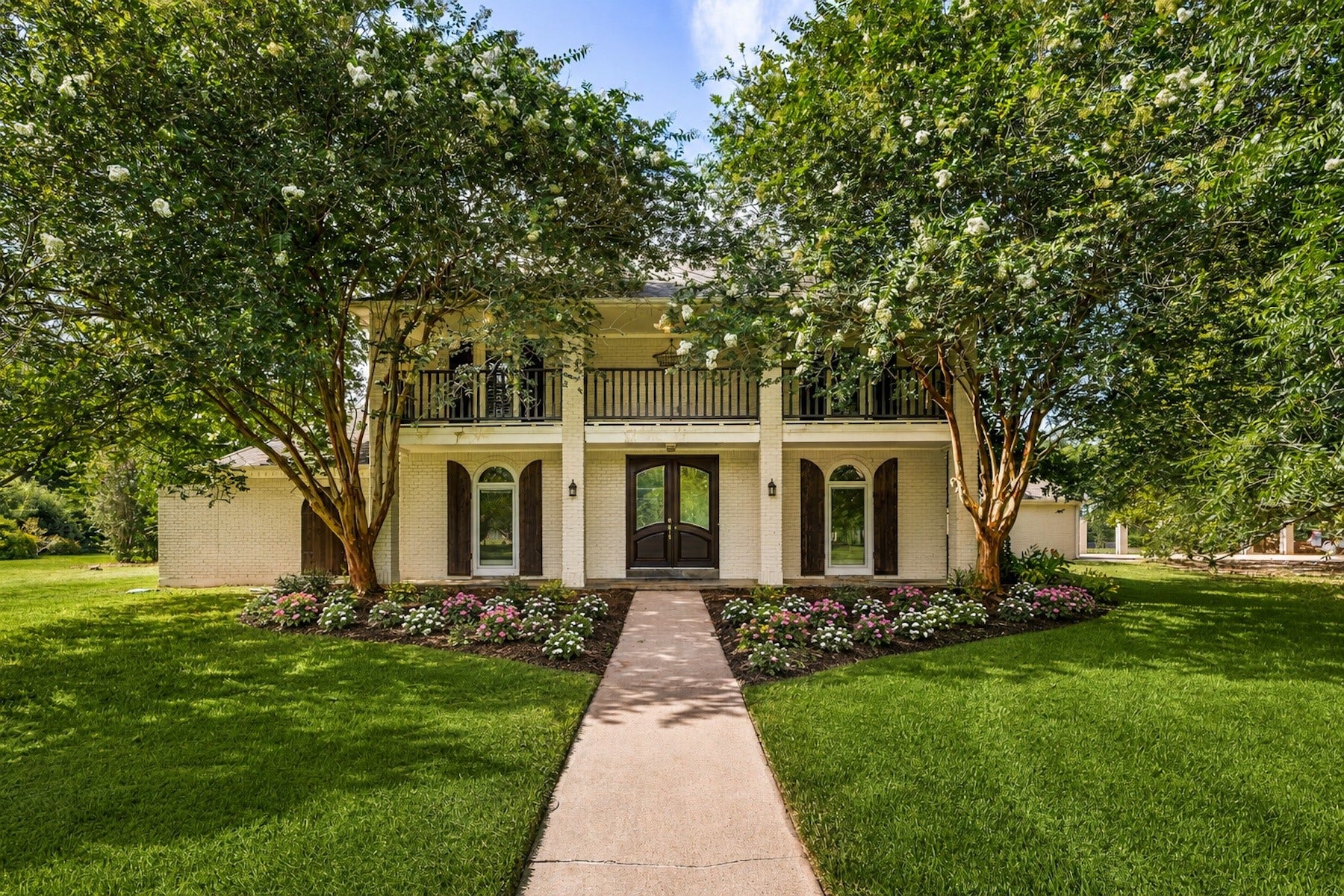 Elegant elevation showcasing timeless architecture and mature crepe myrtles as shade trees along the home.