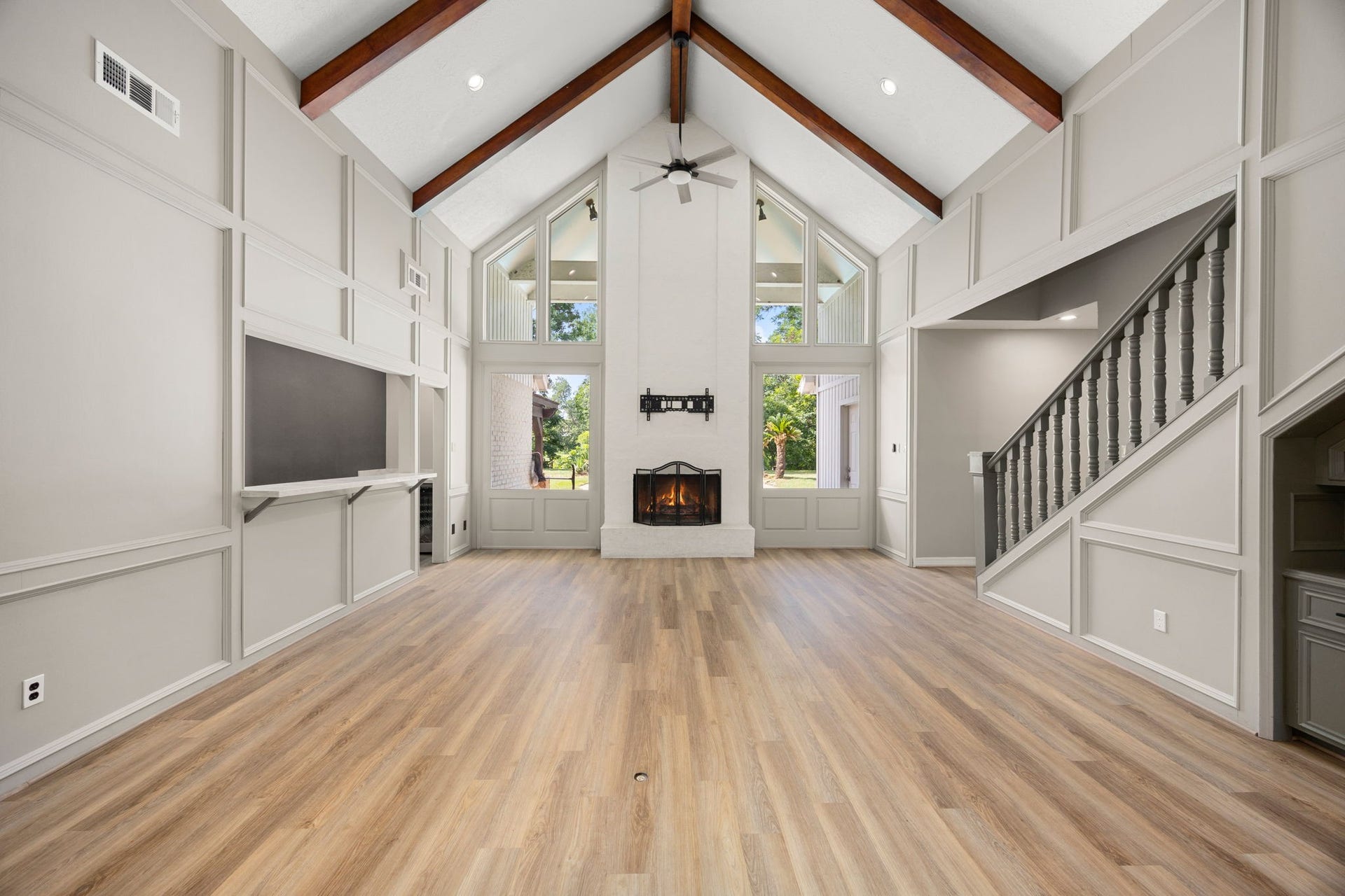 Soaring cathedral ceilings frame the dramatic living room, while the built-in wet bar on the left creates the perfect space for entertaining. Wood burning fireplace adds a focal point to the room while allowing for picturesque views of the backyard.