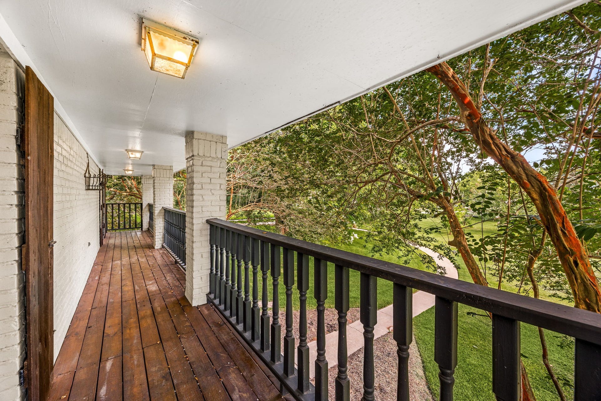 Covered balcony with access through the secondary bedrooms upstairs overlooking the peaceful, wooded grounds.