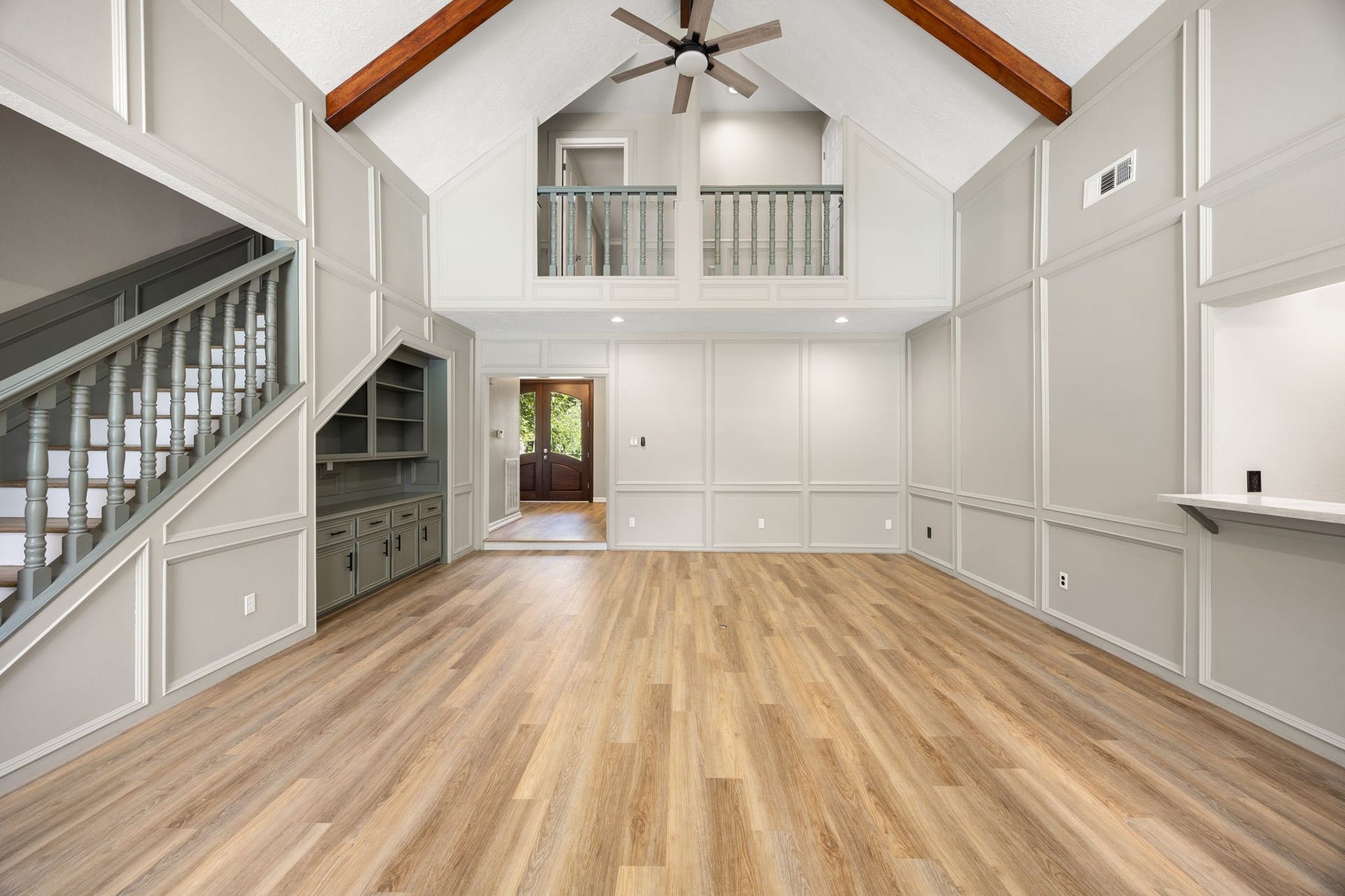 The heart of the home features soaring vaulted ceilings, exposed wood beams, custom built-ins, and a second-floor hallway that creates an airy, open feel throughout the living space.