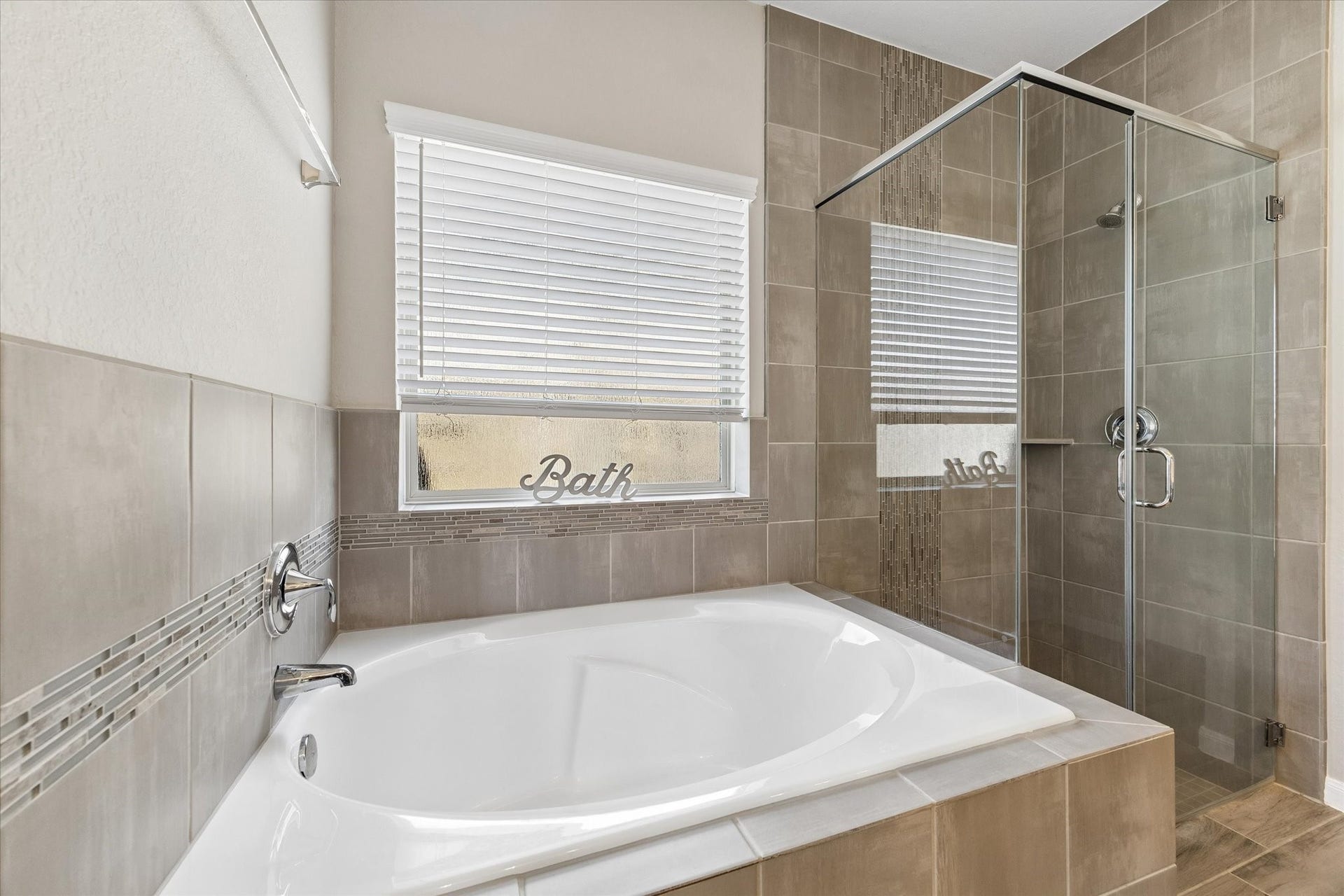 14918 Lake Shore Avenue, Mont Belvieu, TX 77523 Enjoy a quiet reset in the soaking tub, positioned beside a separate glass-enclosed shower with coordinating tile surrounds.