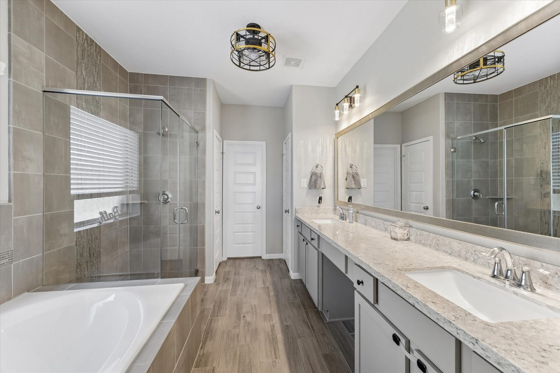 14918 Lake Shore Avenue, Mont Belvieu, TX 77523 The first-floor primary bathroom offers a spacious retreat with dual sinks, generous vanity storage, a soaking tub, and a separate glass-enclosed shower.