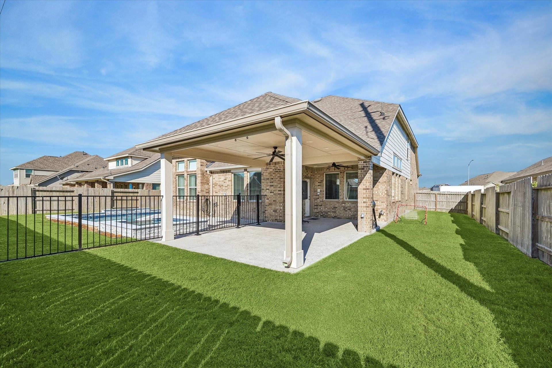 14918 Lake Shore Avenue, Mont Belvieu, TX 77523 Room to swim, gather, and play. The extended covered patio overlooks a privacy-fenced backyard with lush Bermuda grass, replaced in 2024, and open lawn beyond the pool.