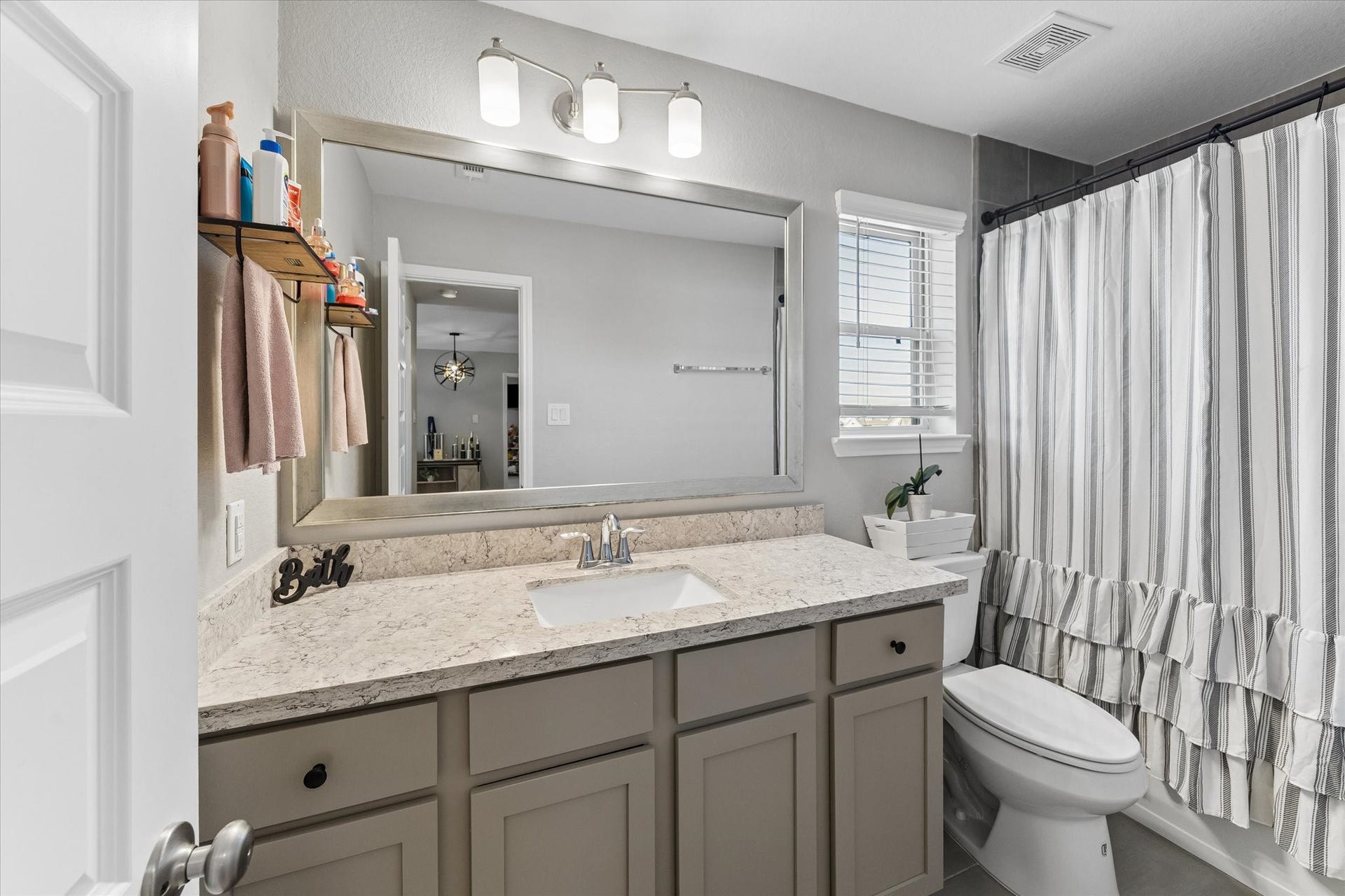 14918 Lake Shore Avenue, Mont Belvieu, TX 77523 Conveniently located near the upstairs secondary bedrooms, this full bathroom offers vanity storage, a wide mirror, and a tub-and-shower combination.