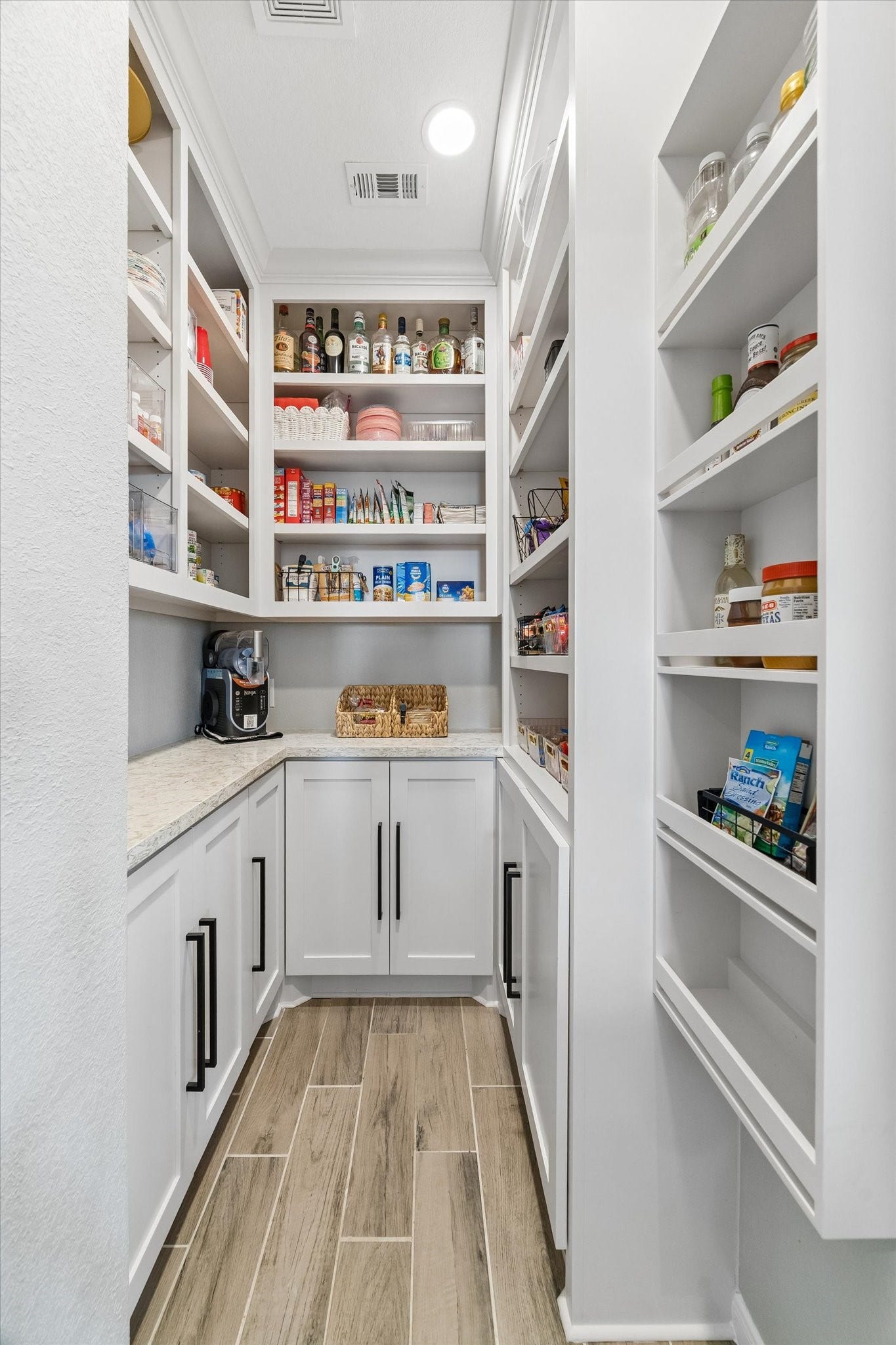 14918 Lake Shore Avenue, Mont Belvieu, TX 77523 Thoughtfully redesigned in 2023, this walk-in pantry features custom cabinetry and shelving, a stone countertop for small appliances, and a built-in coffee bar with cabinets and drawers to keep everyday essentials beautifully organized.