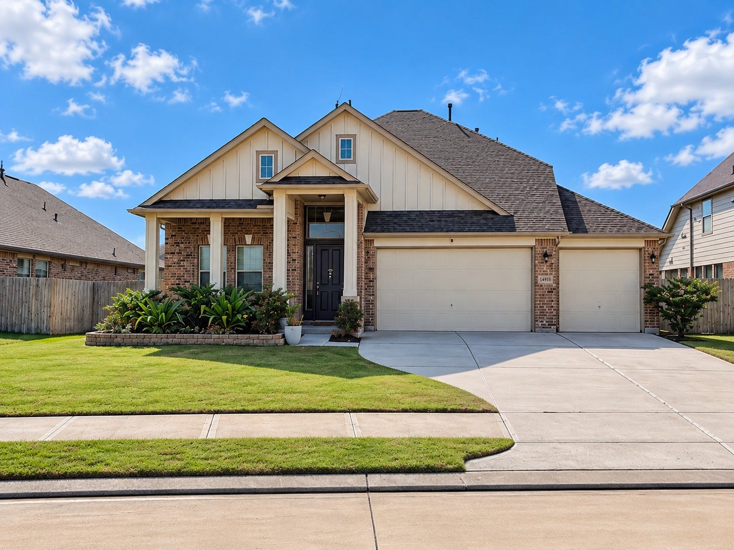 14918 Lake Shore Avenue, Mont Belvieu, TX 77523 Stone-edged landscape beds frame the brick exterior, while board-and-batten gable accents, paneled porch columns, and brick paver flooring add character to the welcoming entry.
